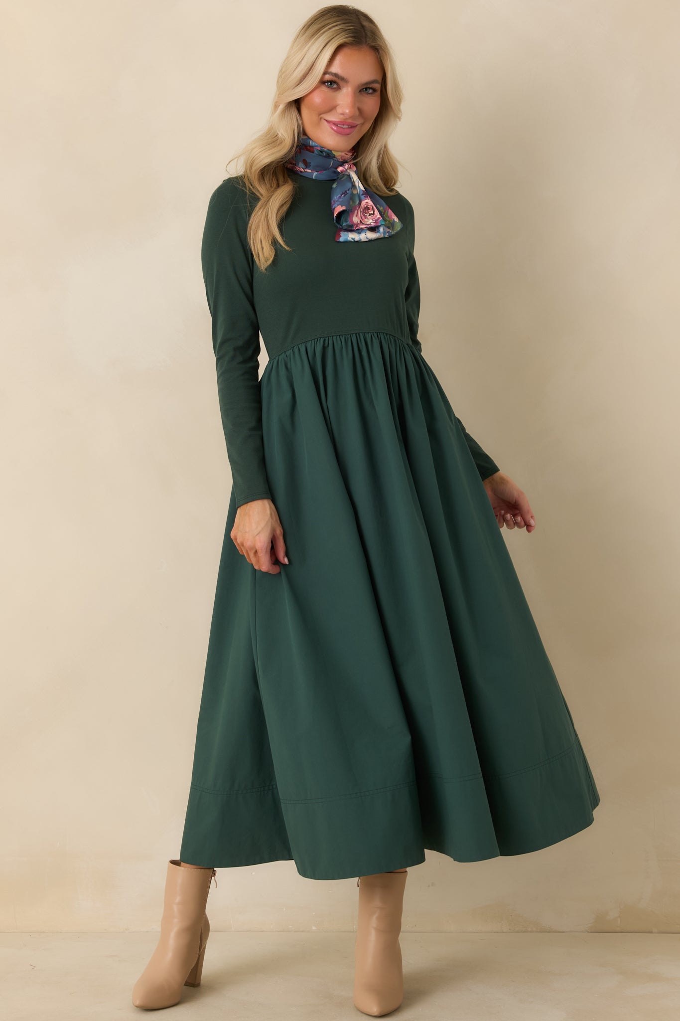 Long sleeve green midi dress with a fitted upper bodice, defined gathered waist, and full cotton skirt falling below the knee.