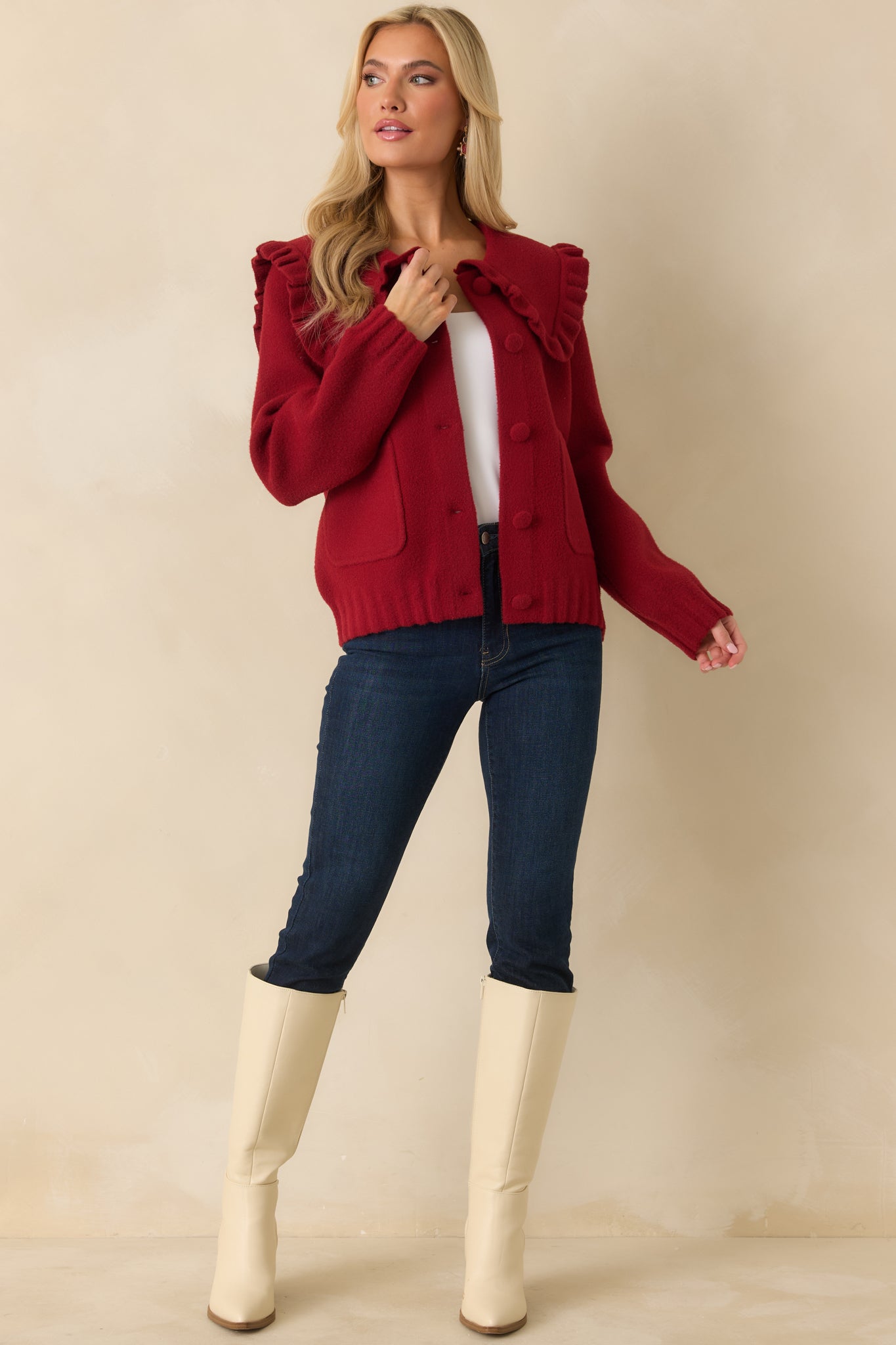 Long-sleeve red cardigan featuring ribbed trim, ruffle neckline, and polished button closure.
