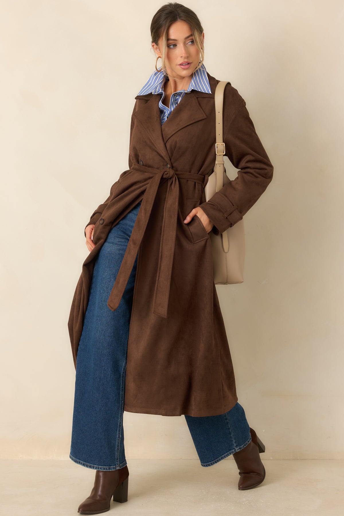 Long tailored coat features a matching waist tie, functional side pockets, and a fully lined interior for comfortable coverage.