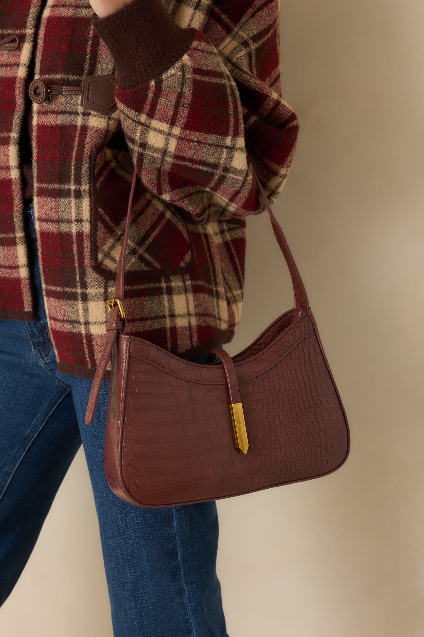 Up-close look at the croc texture, brushed-gold closure tip, and refined hardware details on the rich brown bag.