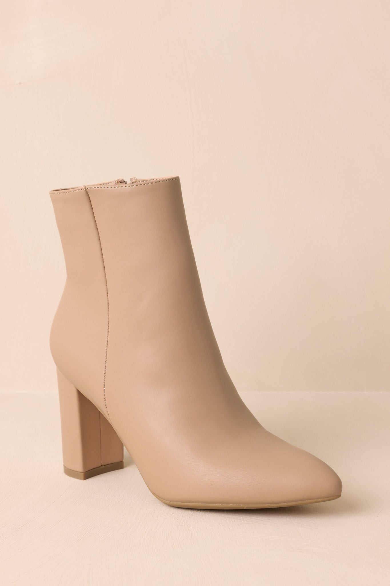 Low-angled shot of beige ankle boots highlighting the height and balance of the block heel.
