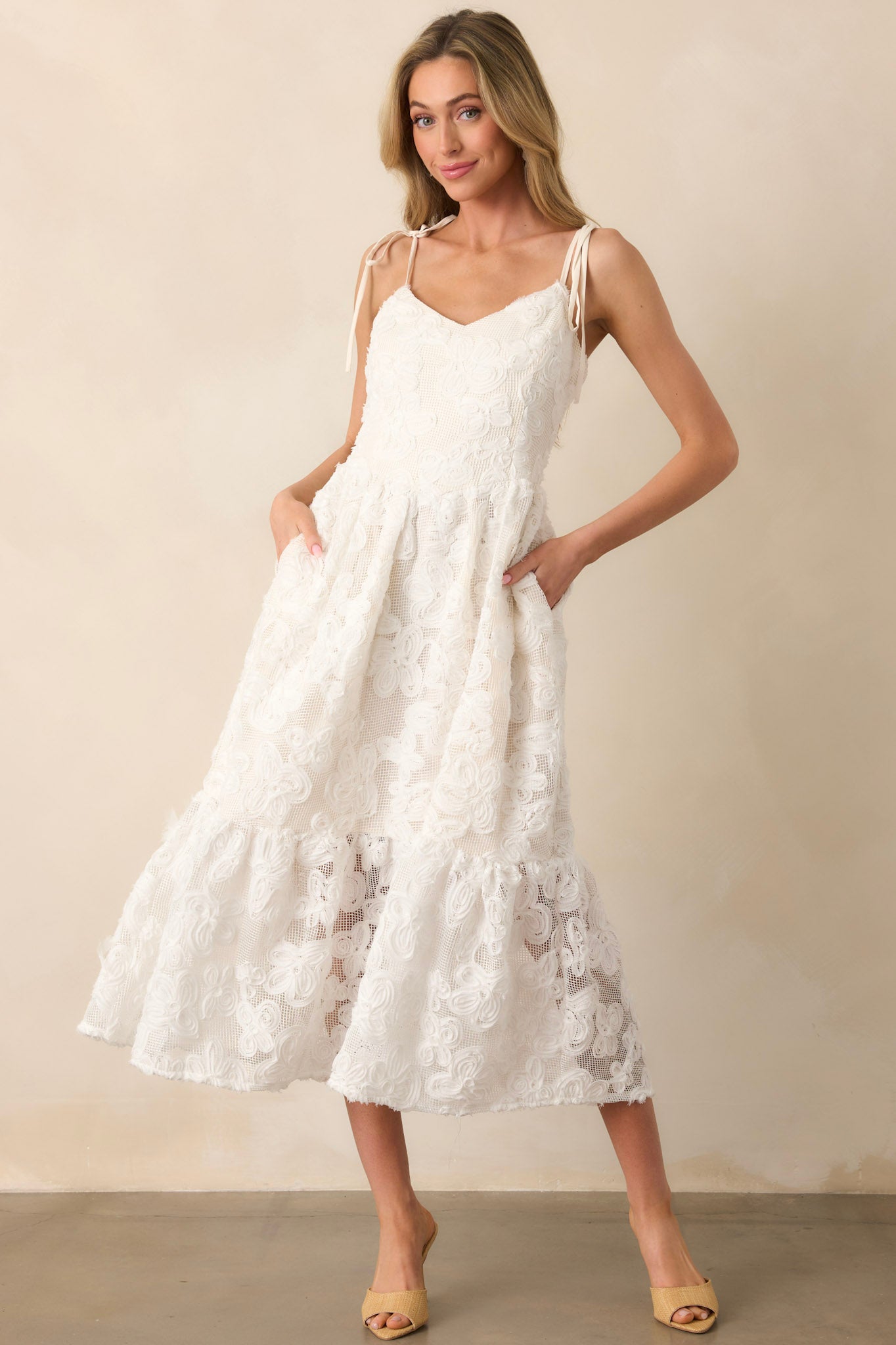 The lower portion of a floral lace maxi dress, showcasing the sheer lace overlay, mini-length ivory lining, and functional pockets seamlessly integrated into the design.