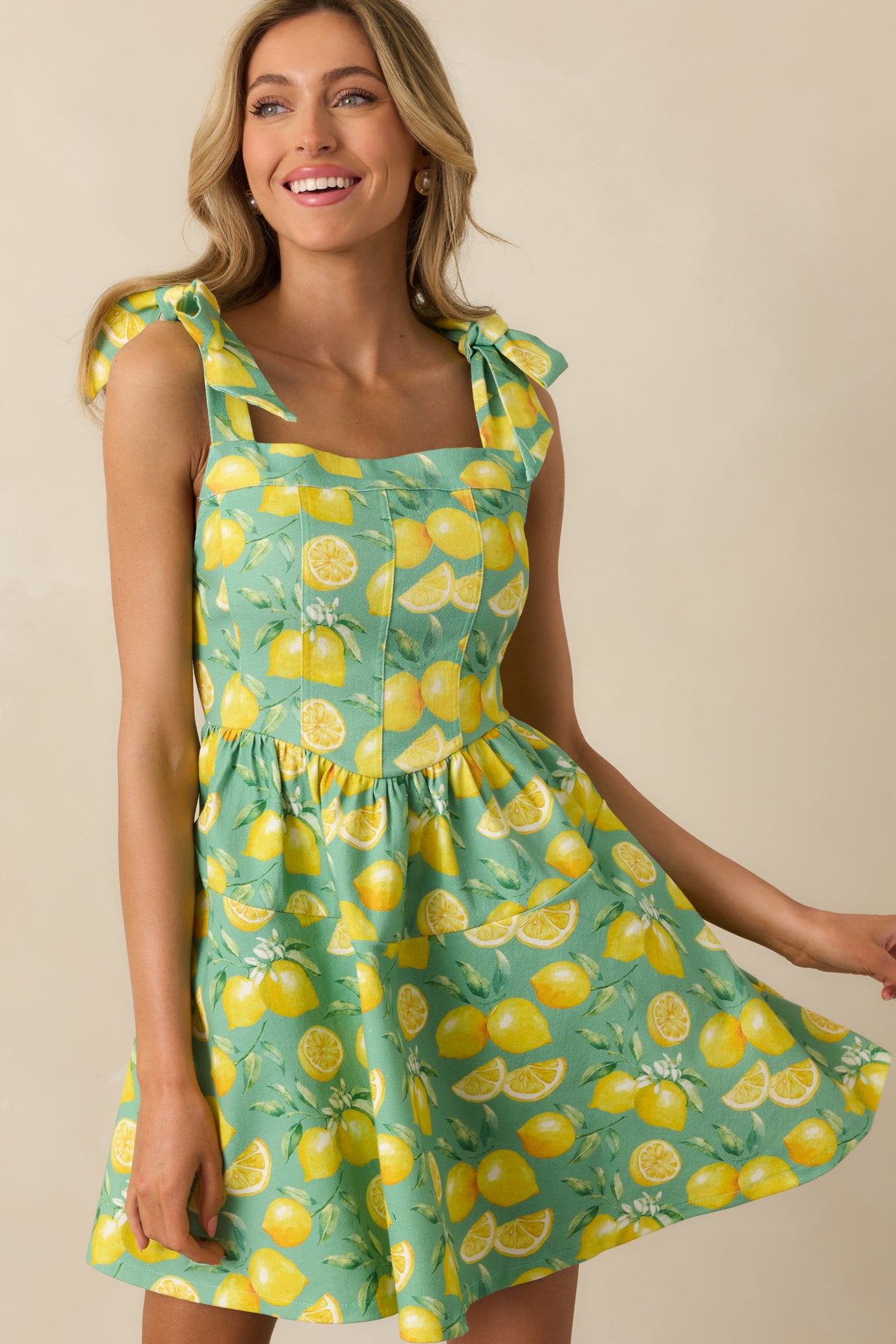 Focused view of the lower portion of the mini dress, showing the drop waist and lemon print fabric.