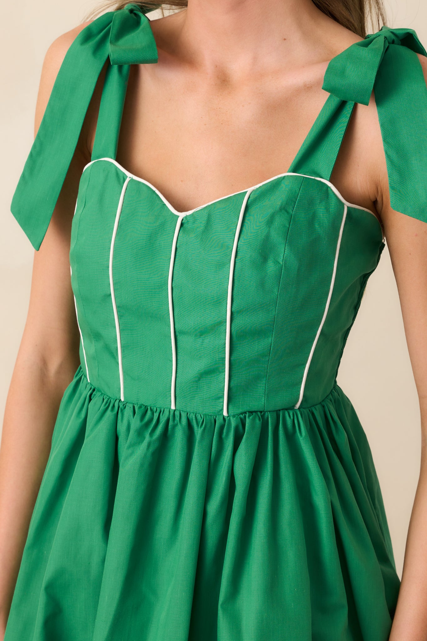 Macro shot of the smocked panel on the green mini dress, displaying elastic texture and stitching details.