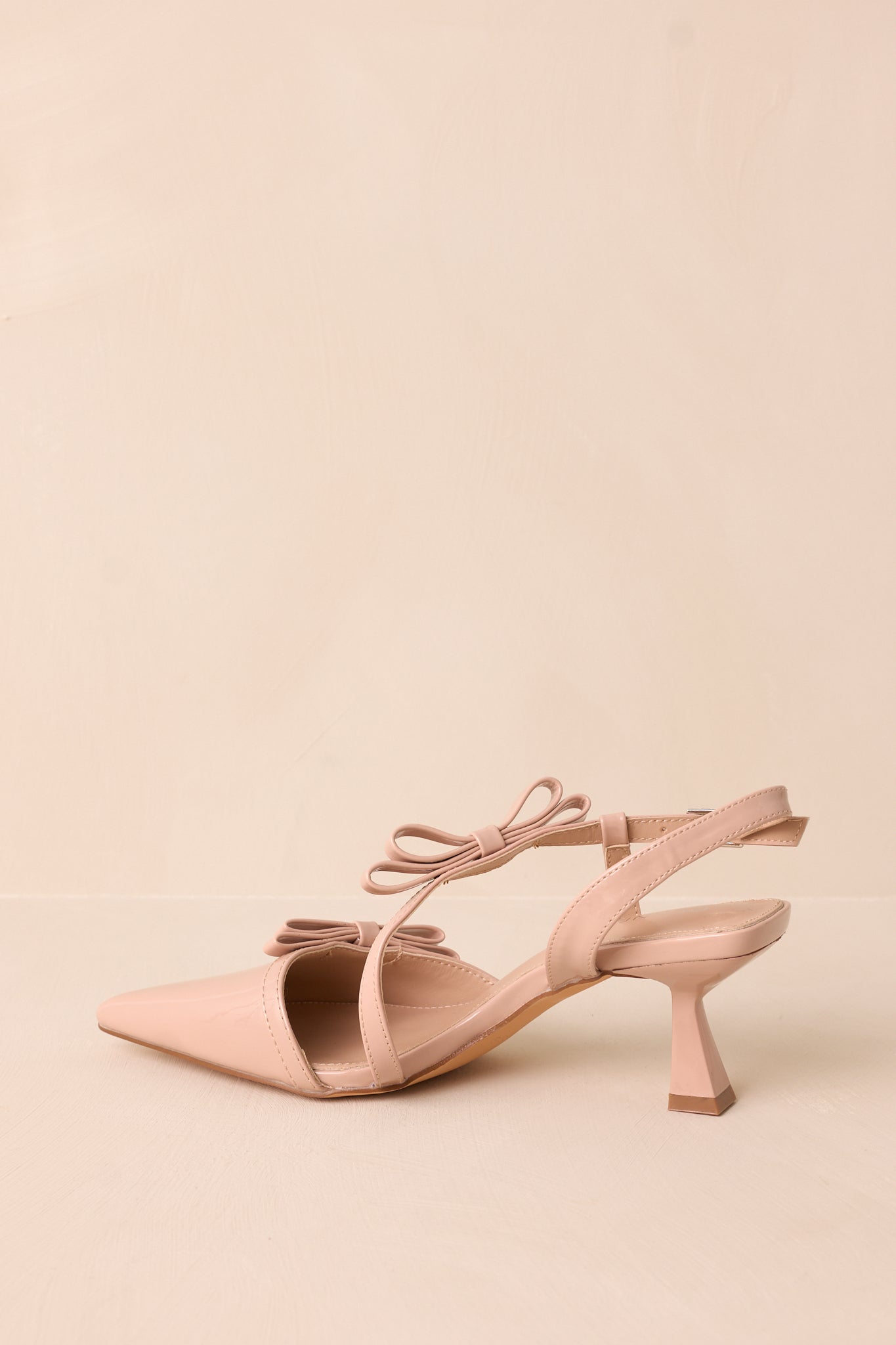 Macro shot emphasizing the texture of the glossy material, the precise stitching, and the delicate bow embellishments.