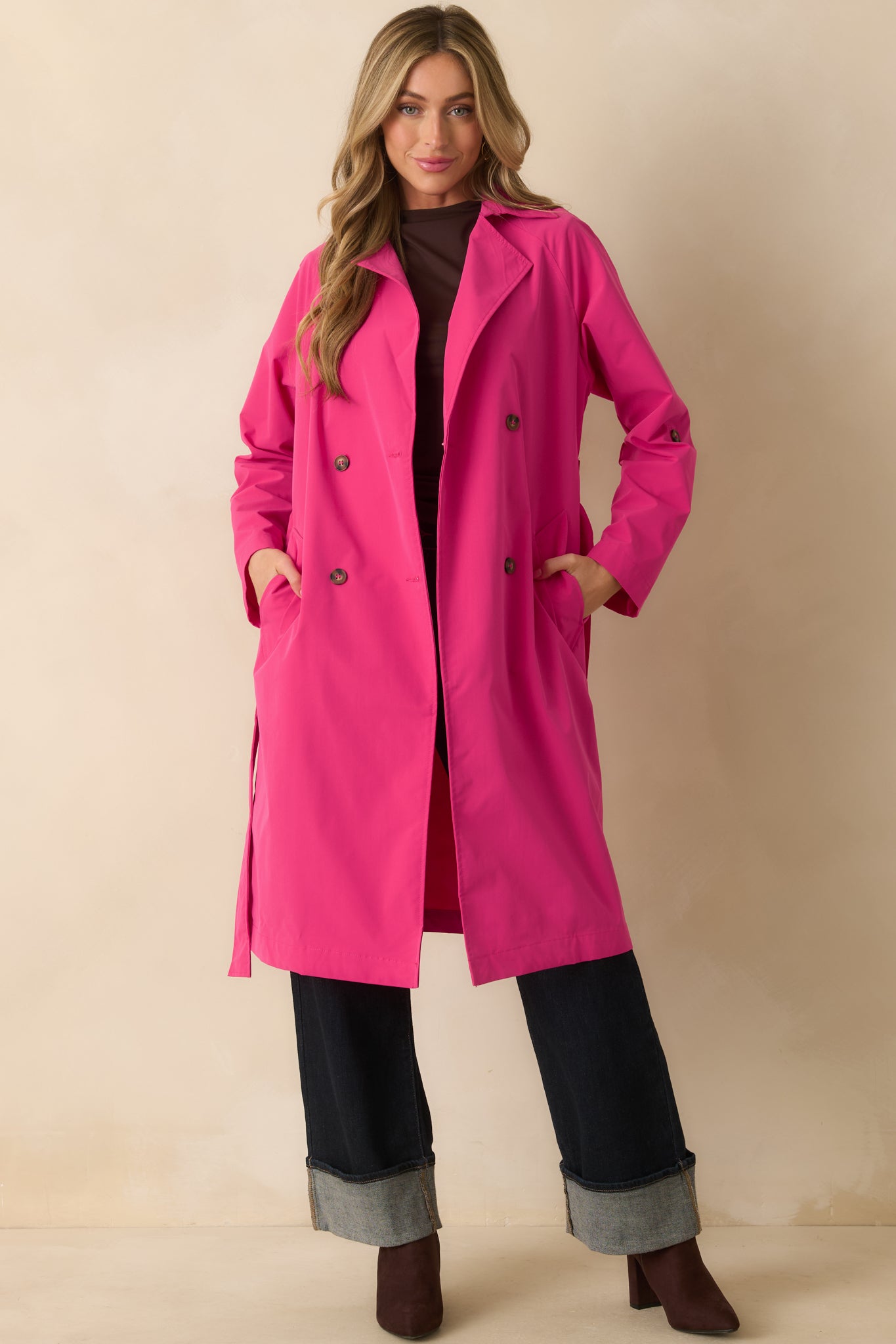 Magenta coat with a collared neckline and double-breasted lapel shown from the front, featuring a self-tie waistband and long sleeves.