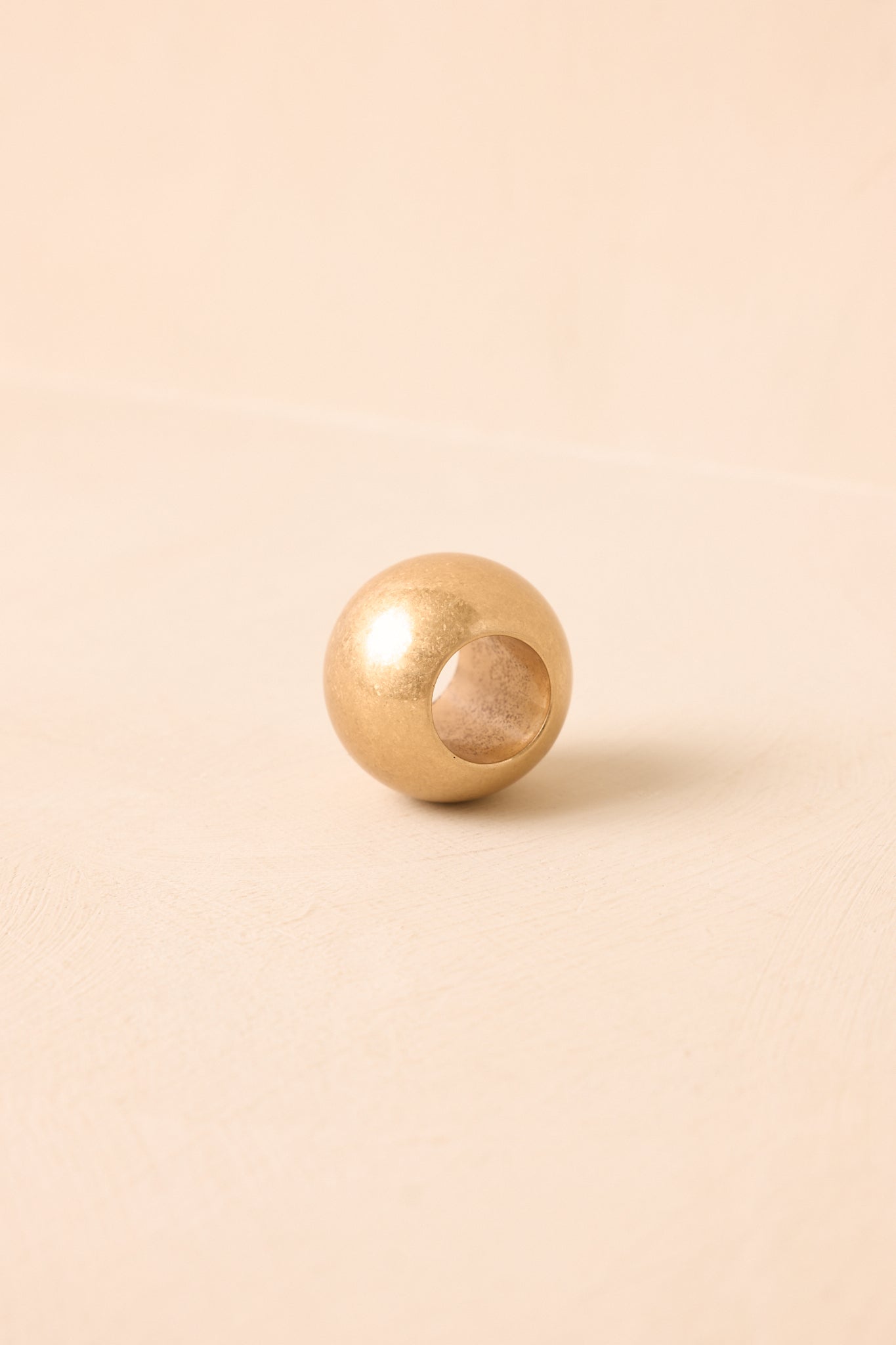 Close-up of the matte gold scarf ring featuring a smooth ball silhouette, brushed finish, and clean modern design.