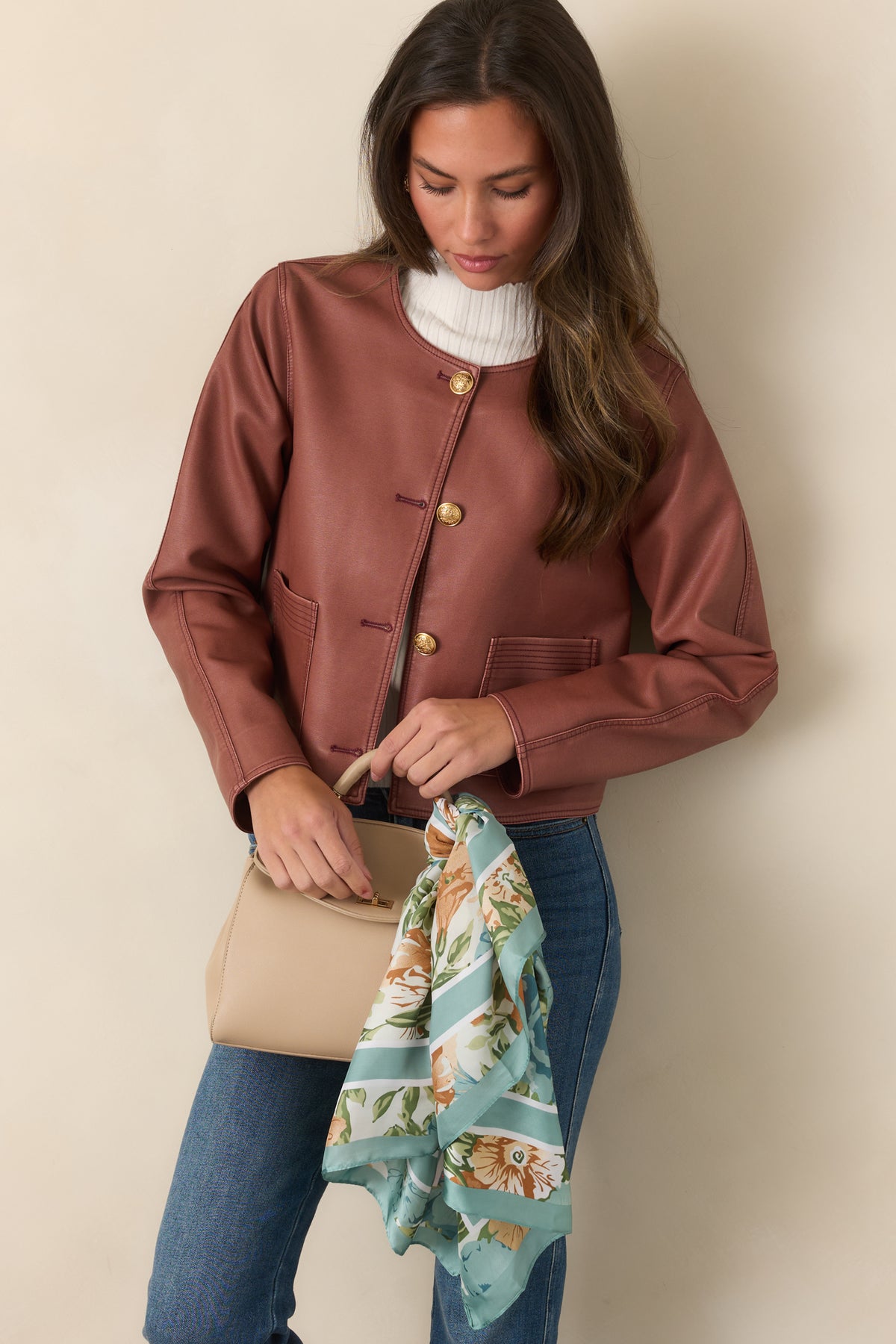 Mauve faux leather jacket showcases its cropped shape, round neckline, and cleanly finished edges.