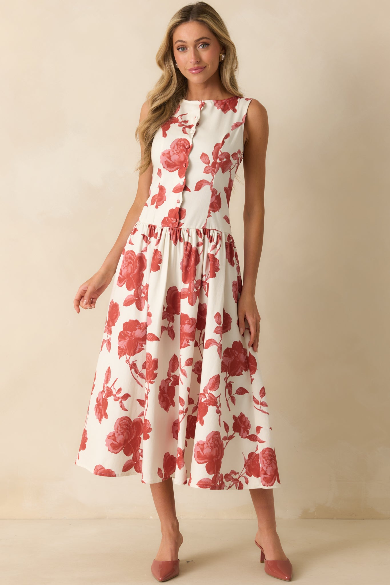 Maxi dress with a paneled bodice and drop waist silhouette in an ivory and brick red floral pattern.