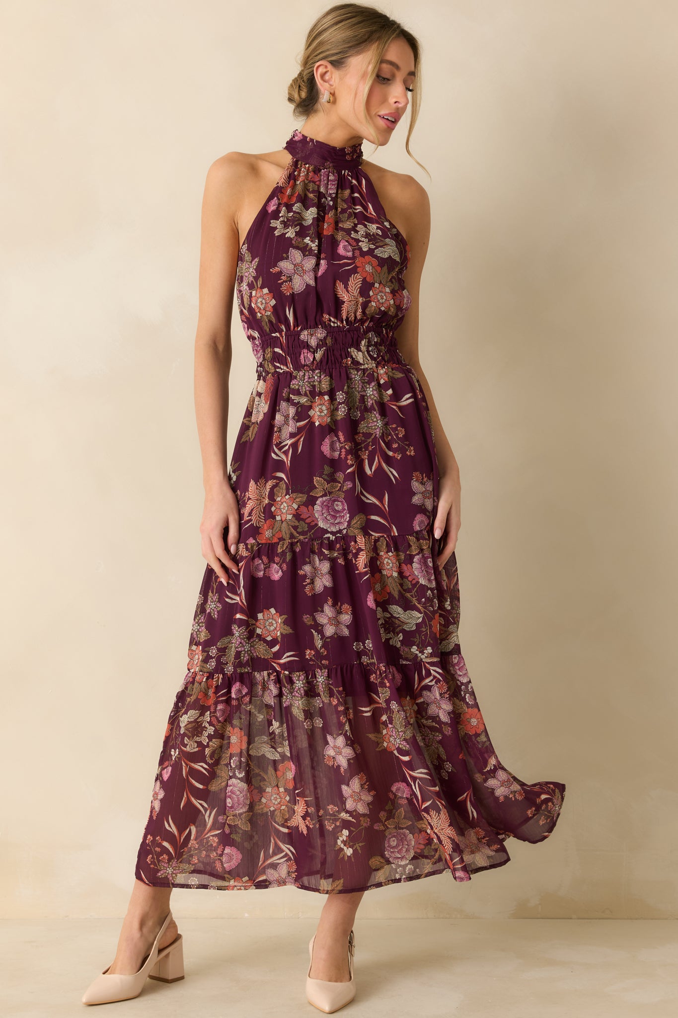 The maxi dress shows its purple multi floral print with a gathered halter neckline and flowing tiered skirt.