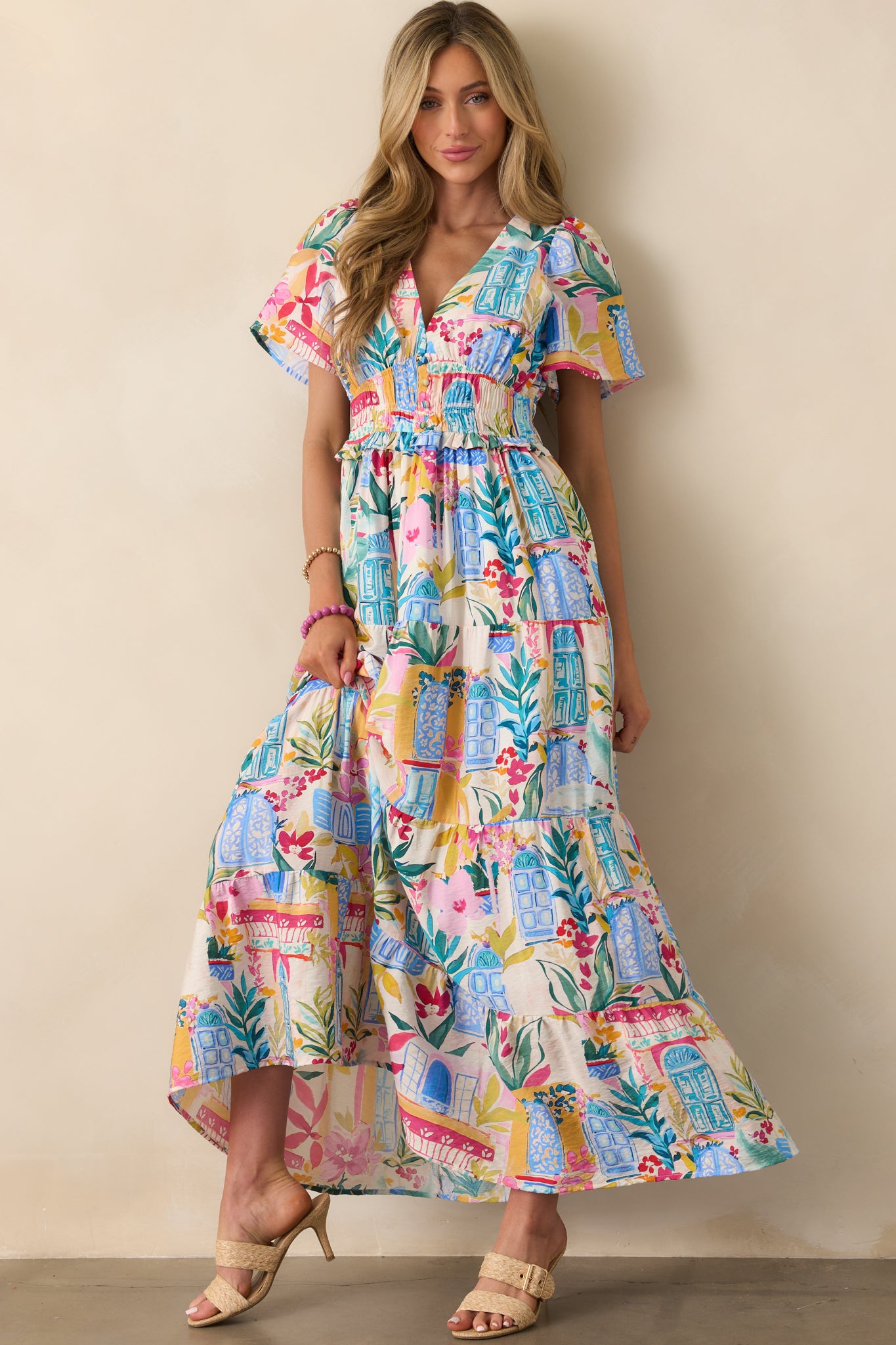 Front view of the maxi dress showcasing the Italian landscape-inspired watercolor print with doors and florals, deep v-neckline, and smocked waist.
