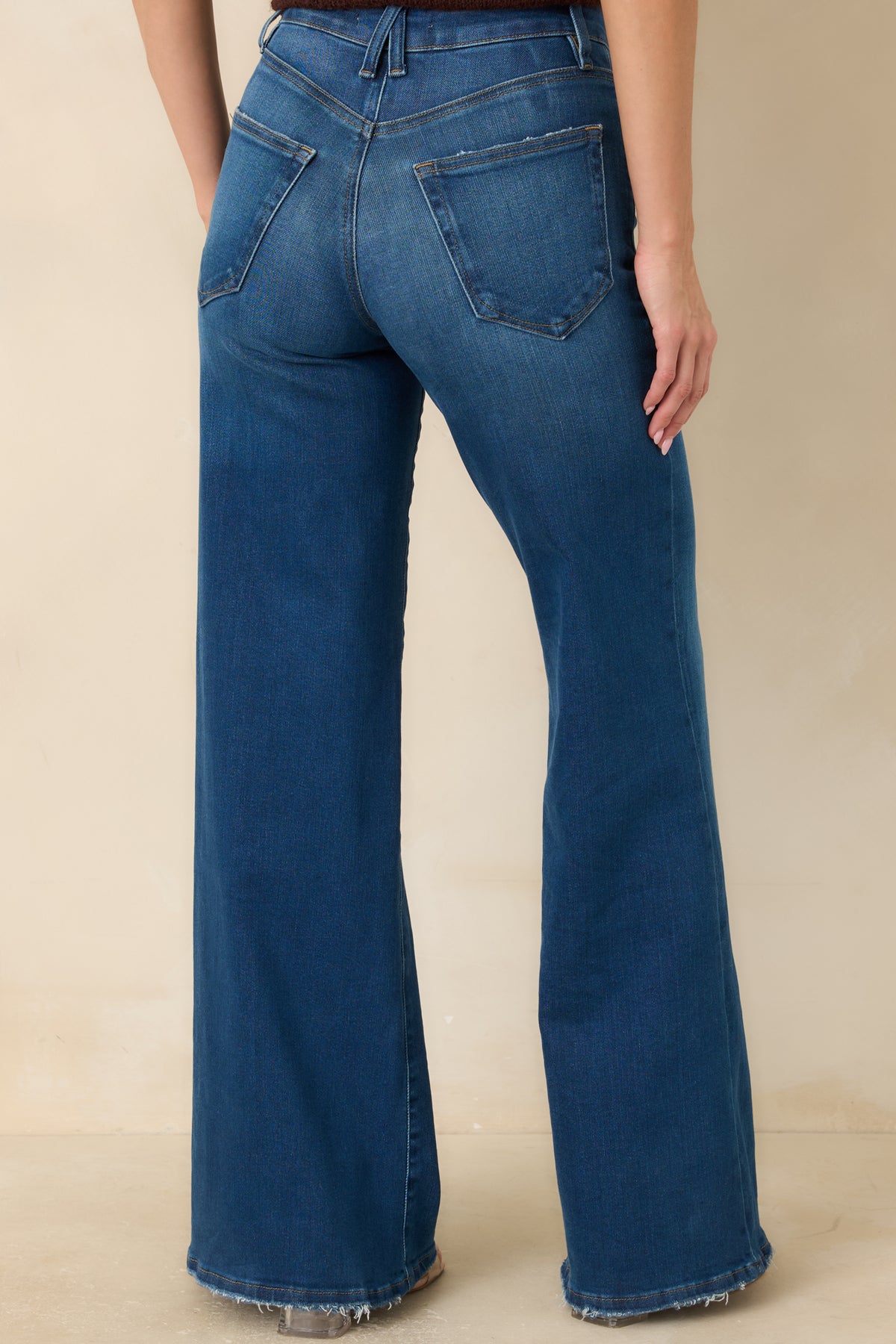 Medium blue palazzo jeans with a high-rise back waistband, rear patch pockets, and full-length wide legs.