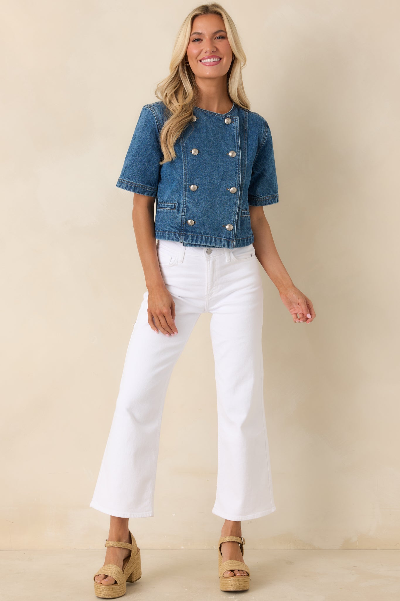 Medium wash cropped denim top with short sleeves and a polished double-breasted front accented by statement gold buttons