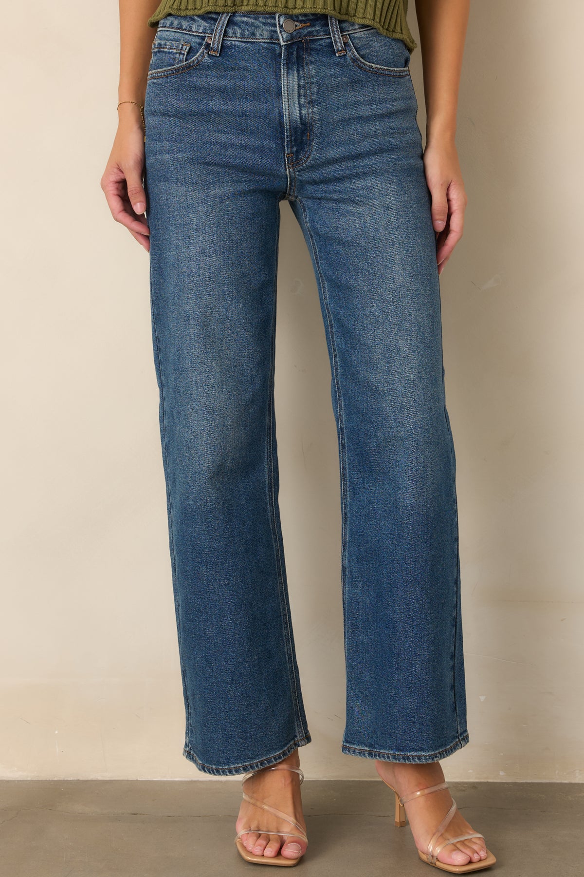 Medium wash denim highlighting the high-rise waist and button and zip closure.