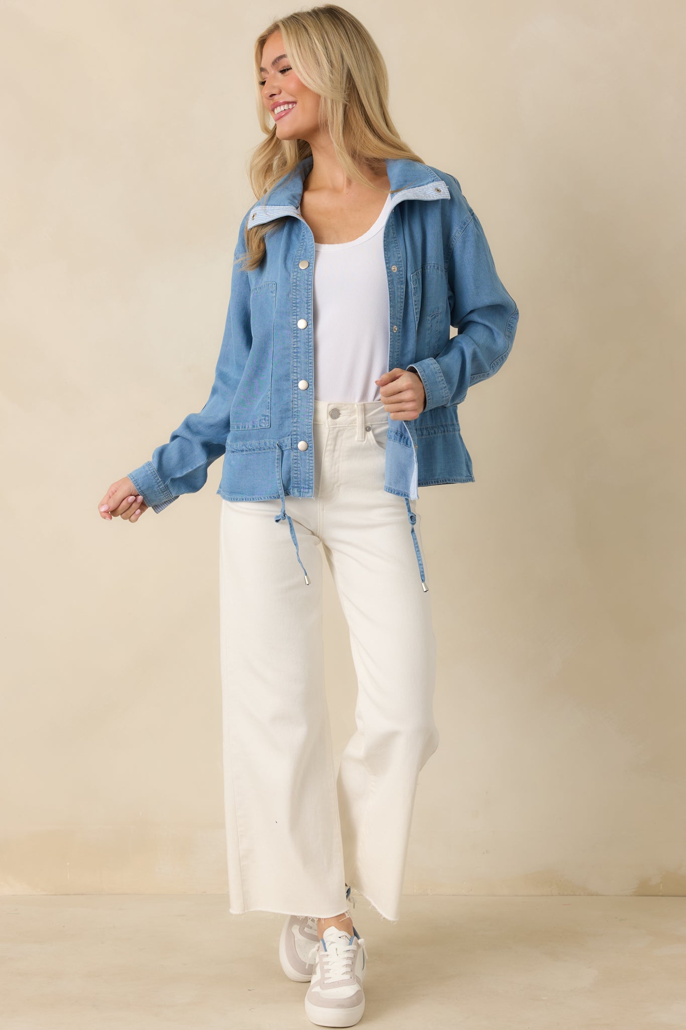 Button-front denim blouse in medium wash featuring long sleeves with snap cuffs and subtle peplum shape.