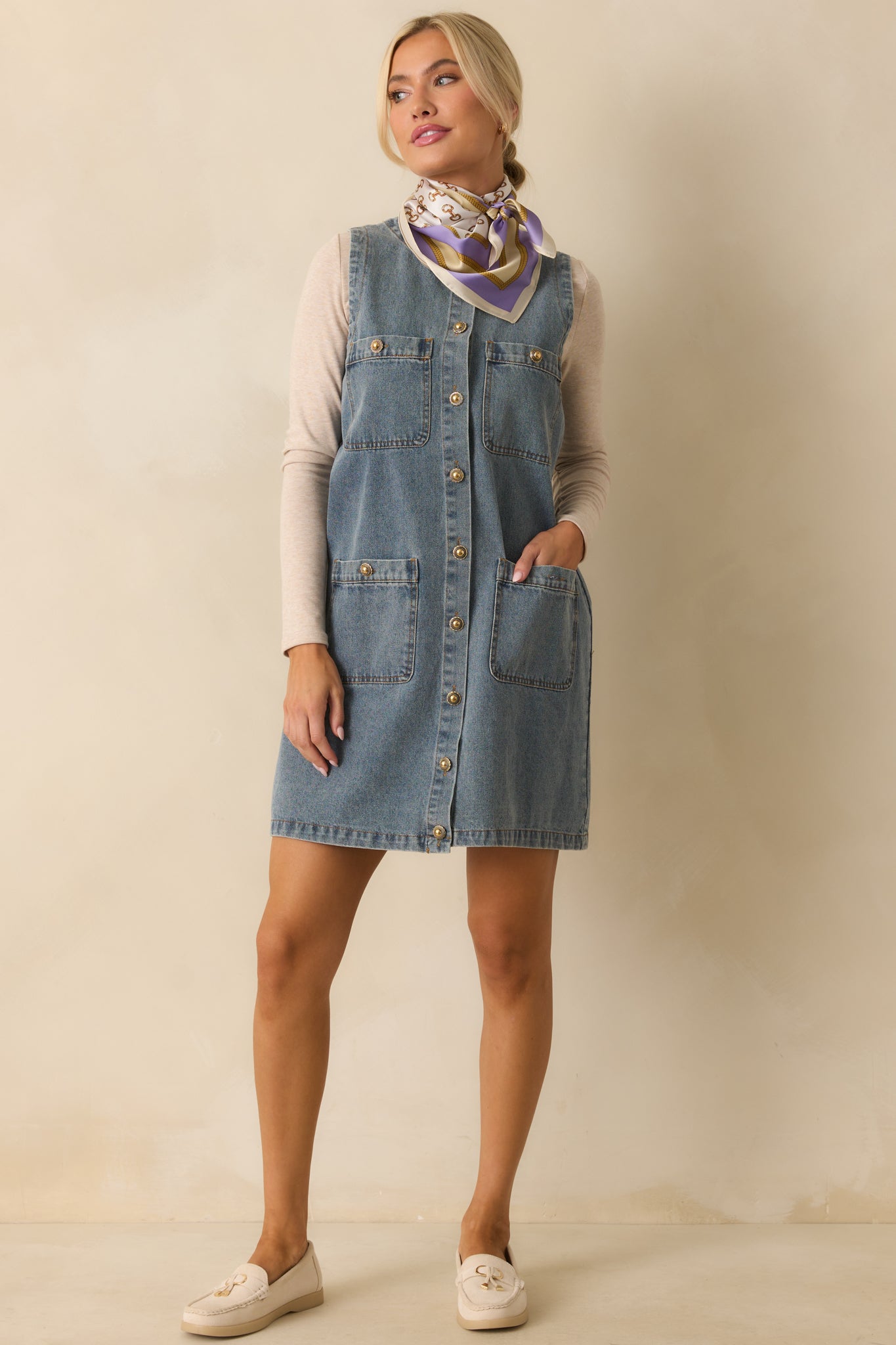 A full-length shot showing the mini dress with functional pockets and medium-wash denim fabric.