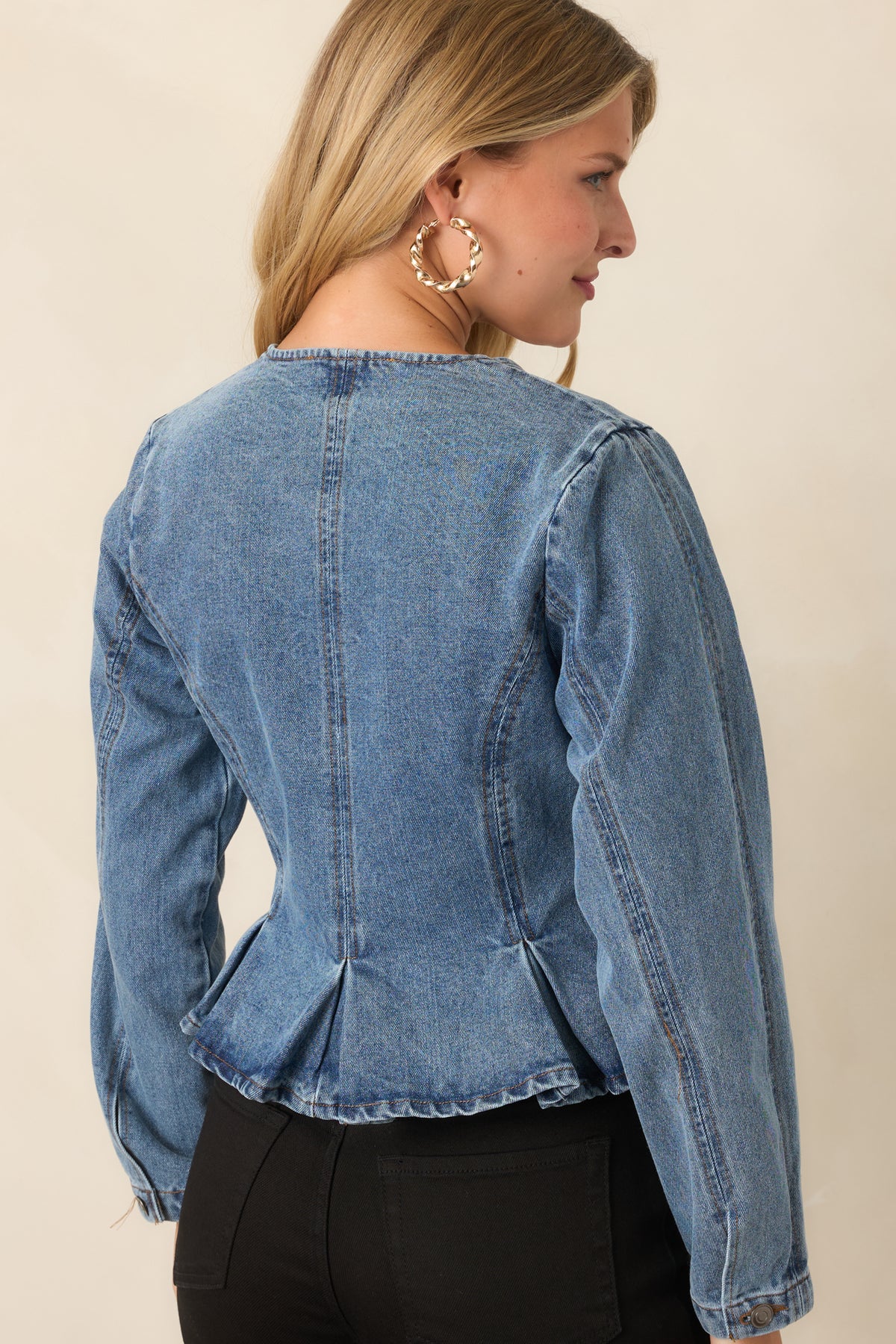 Rear of the medium wash jacket showing its pleated peplum silhouette.