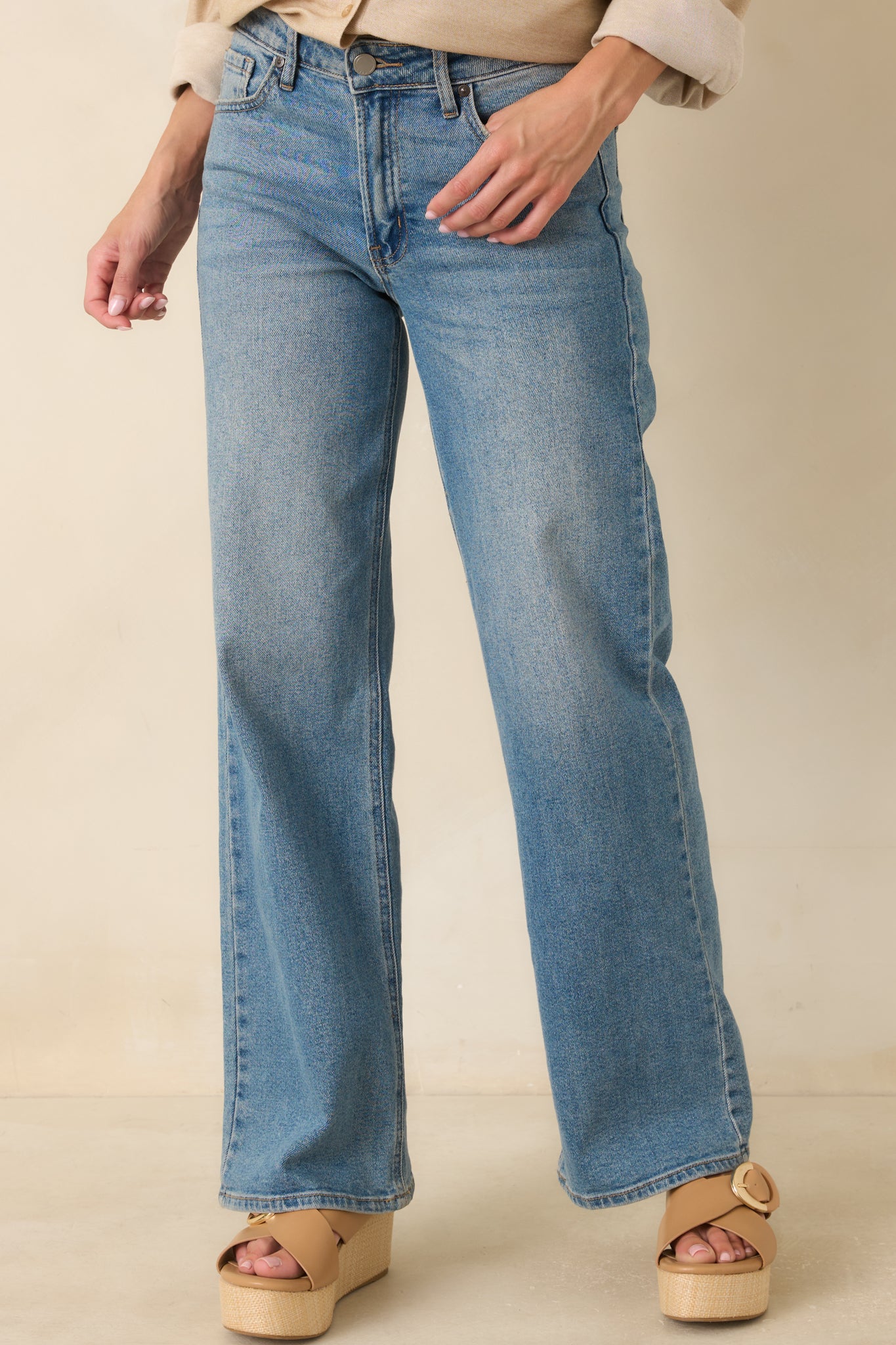 Detailed view of the waistband featuring functional belt loops and a button zipper closure on the medium wash jeans.