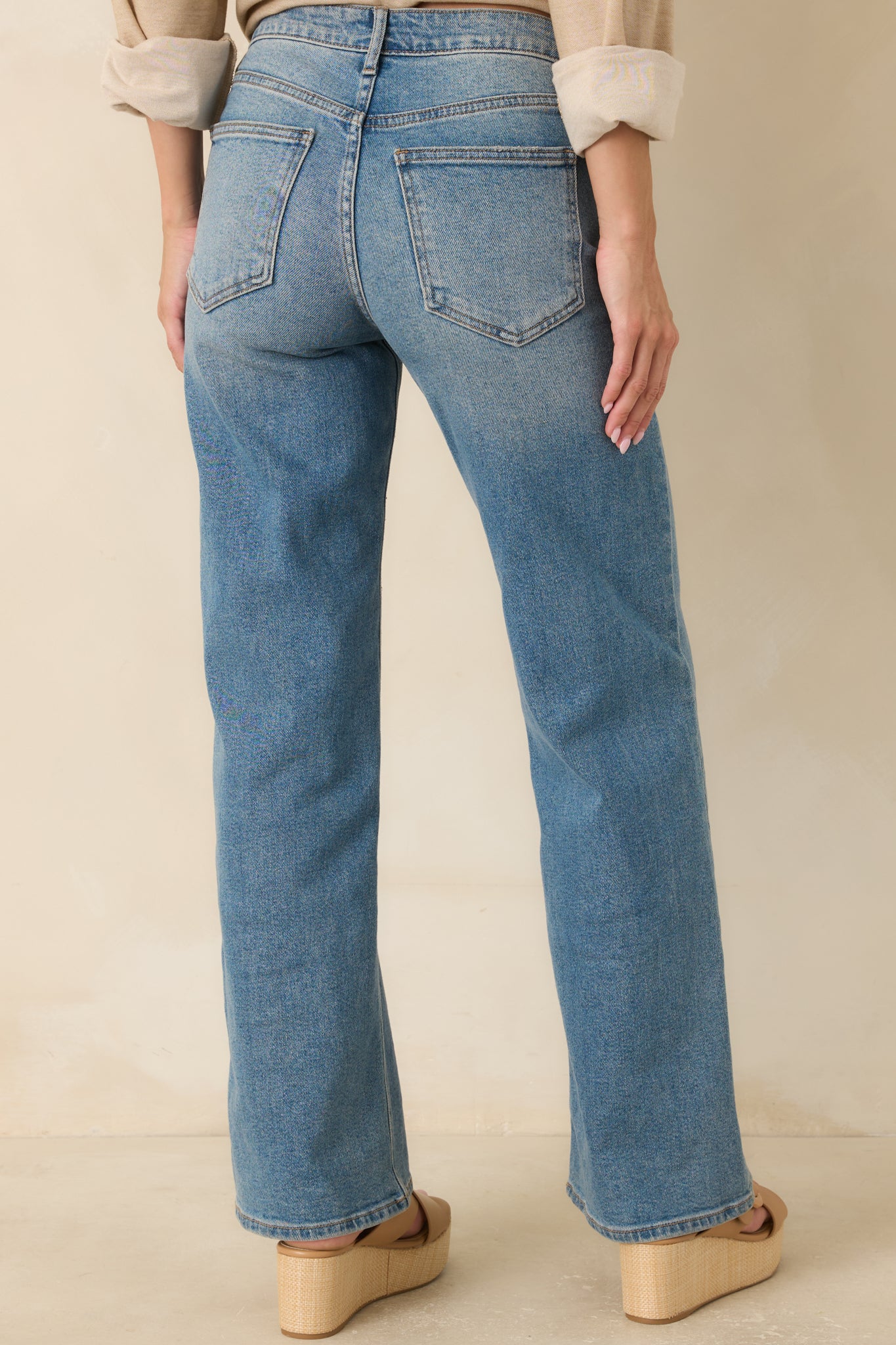 Back view of the medium wash jeans featuring functional back pockets and a relaxed wide leg silhouette.
