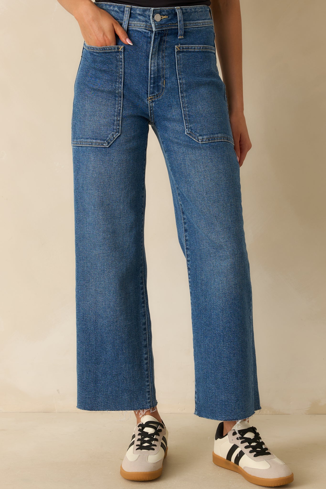 Medium wash utility jeans with high-rise waist, wide-leg silhouette, and raw-cut hem.