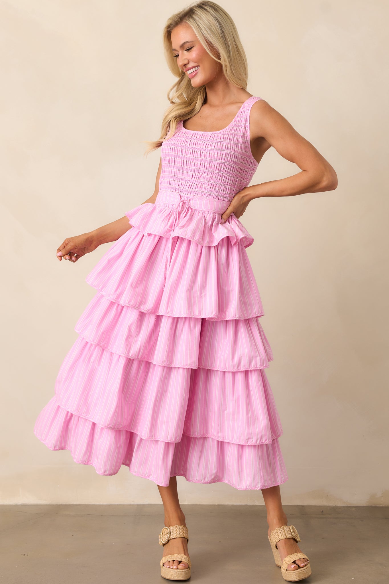 Soft pink stripes flow through this midi dress, complete with a stretchy smocked bodice and a tiered skirt that adds dimension.
