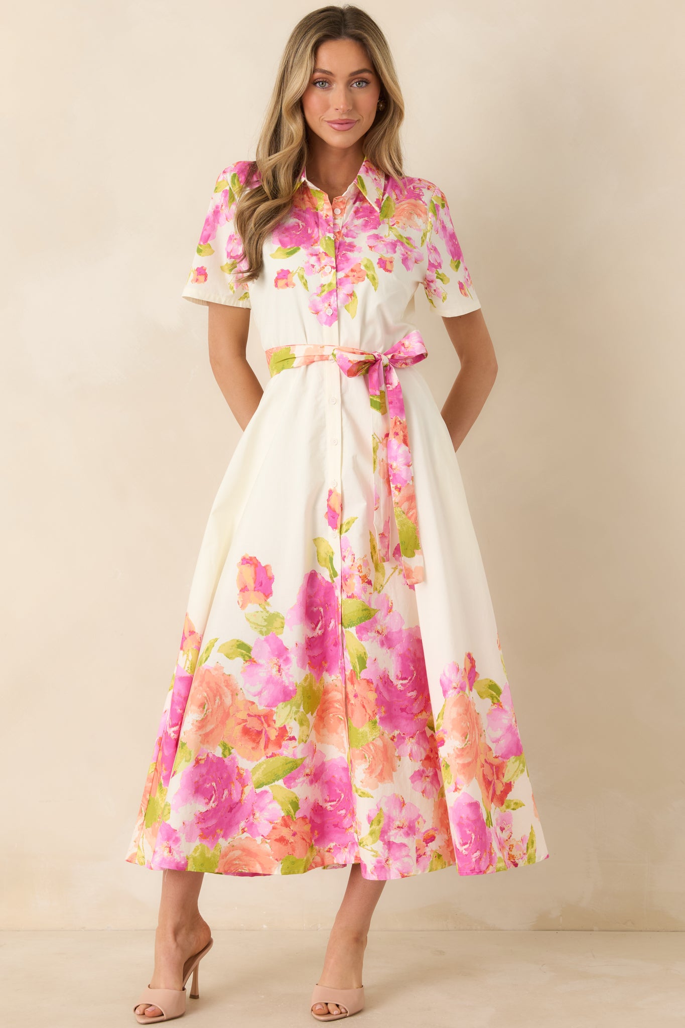 Midi-length dress with collared neckline, defined waist with belt, and colorful blooms along hem.