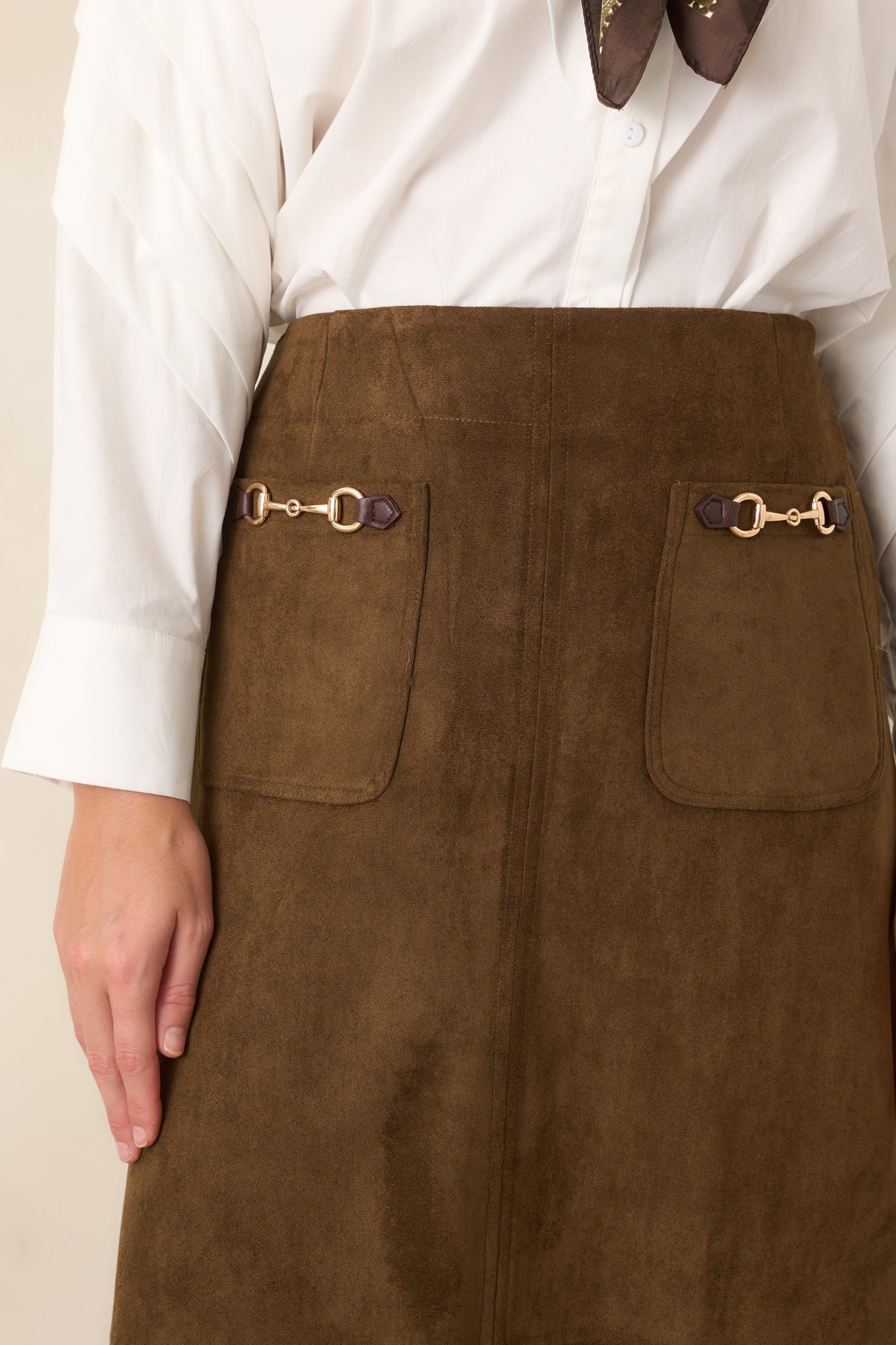 Close-up of the skirt showing decorative gold-tone horse-tack hardware and detailed front pocket accents.