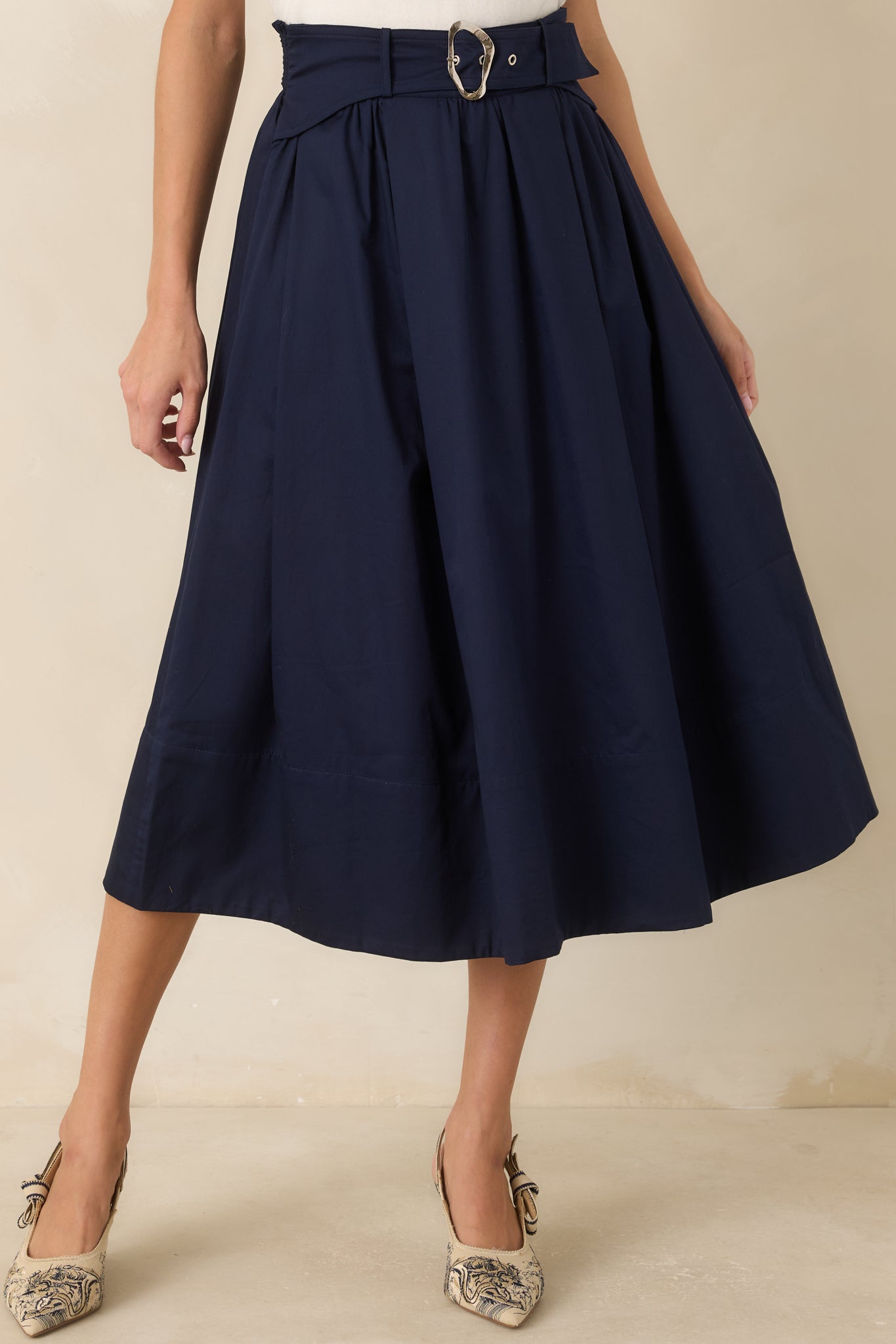 Detailed view of the midi skirt highlighting the pleated construction and integrated belt with sculptural hardware.