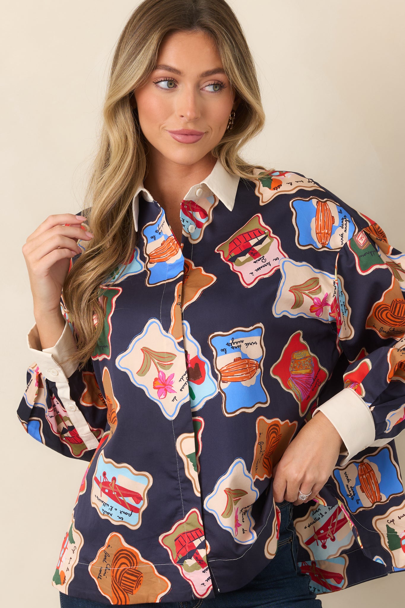 Detailed view of the top's button-front design surrounded by colorful stamp-inspired illustrations on the midnight blue fabric.