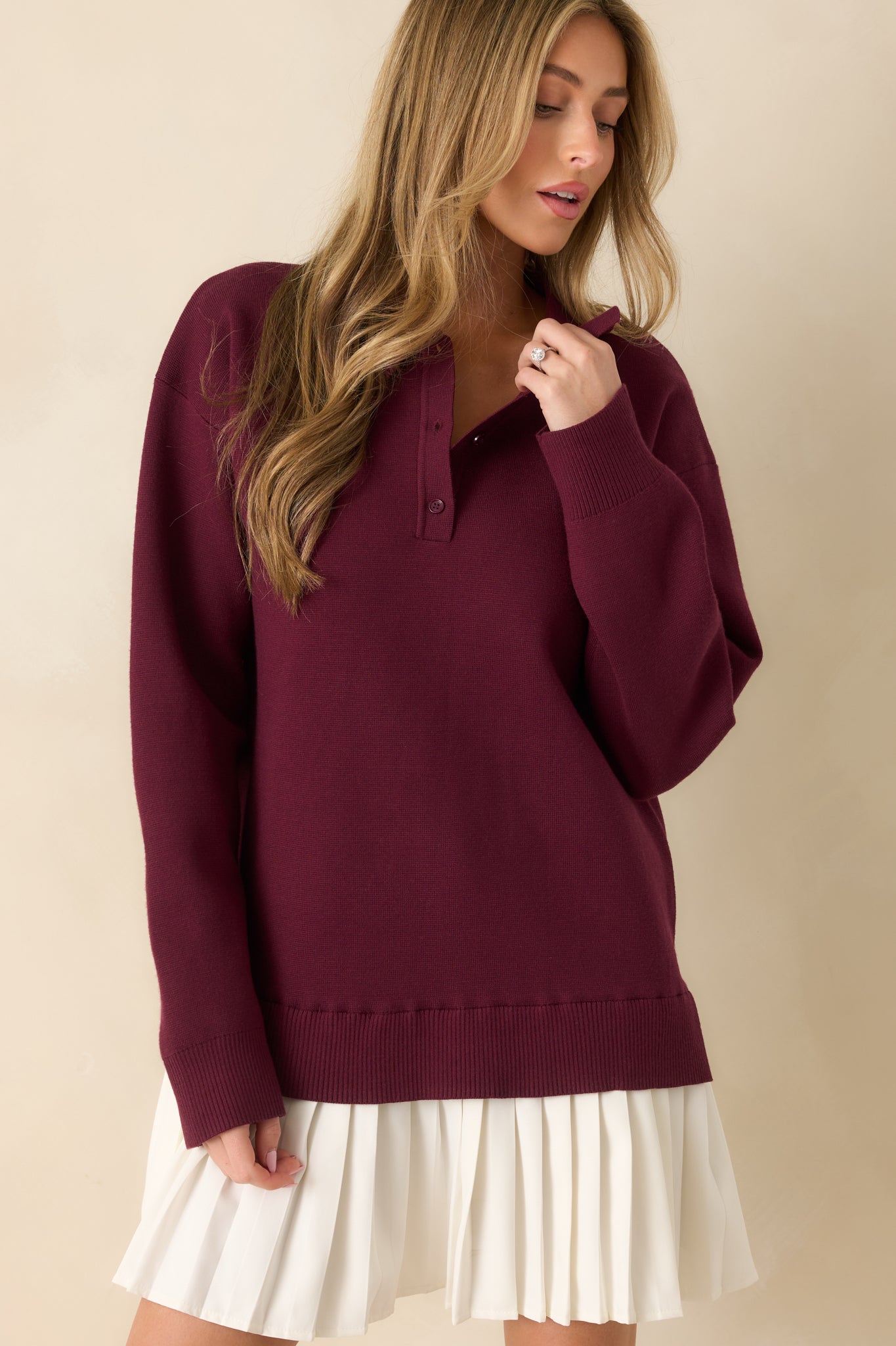 Midsection crop showing ribbed hem, knit texture, and relaxed silhouette of the burgundy dress.