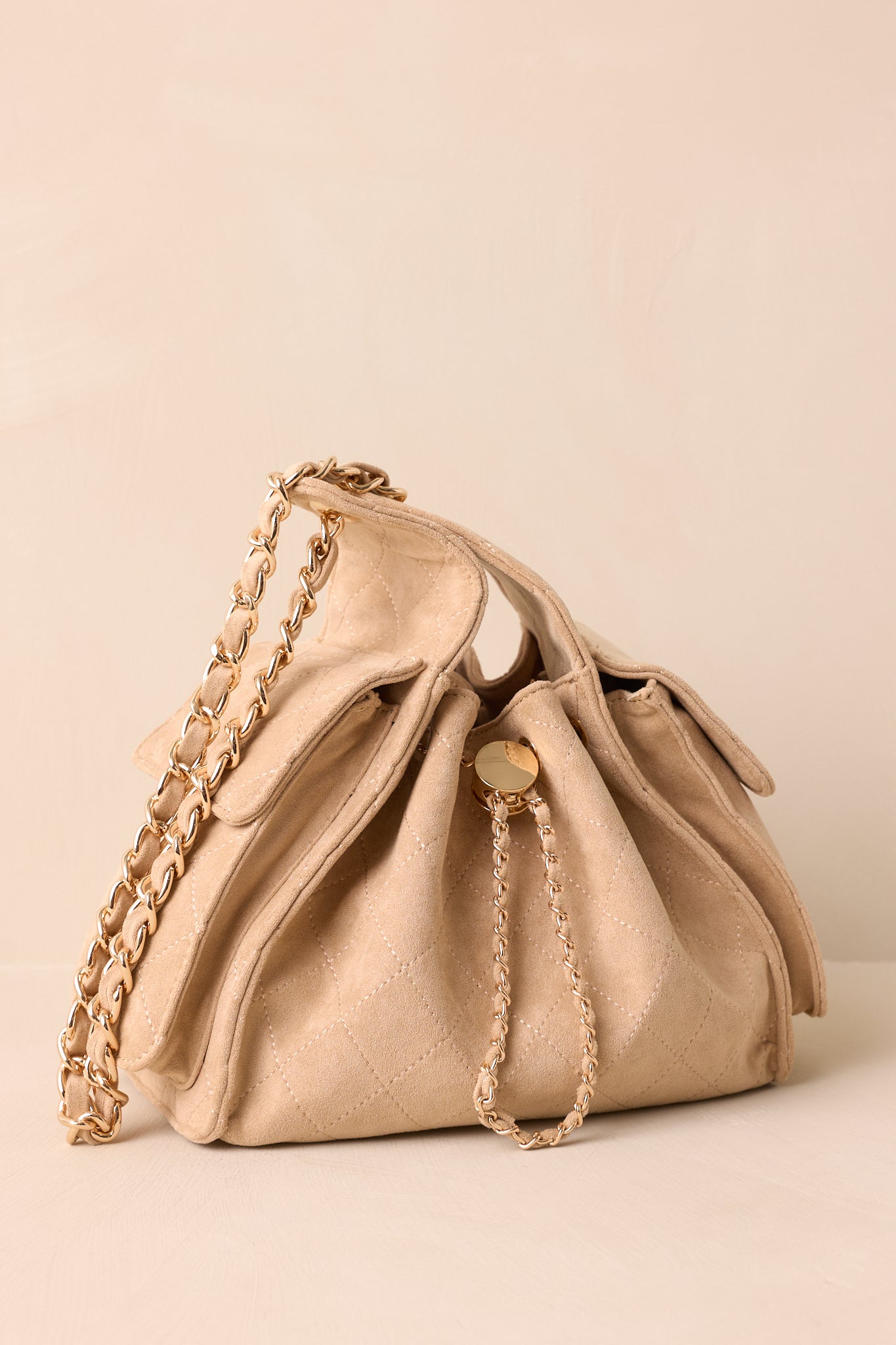 Midsection of taupe purse highlighting fold-over side pocket and woven faux leather and gold drawstring.