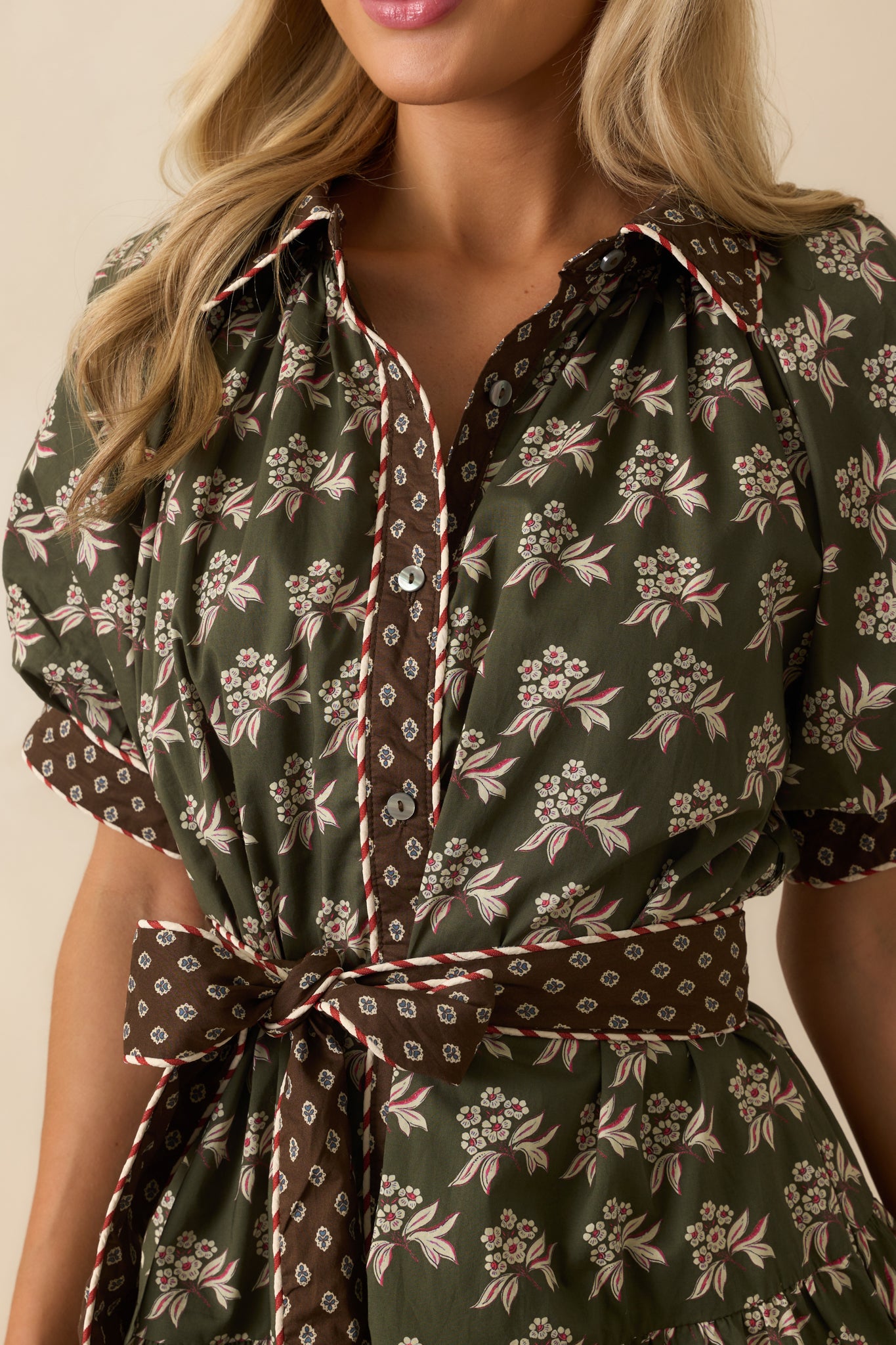 Detailed view of floral print, contrast trim, and button front closure on the mini dress.