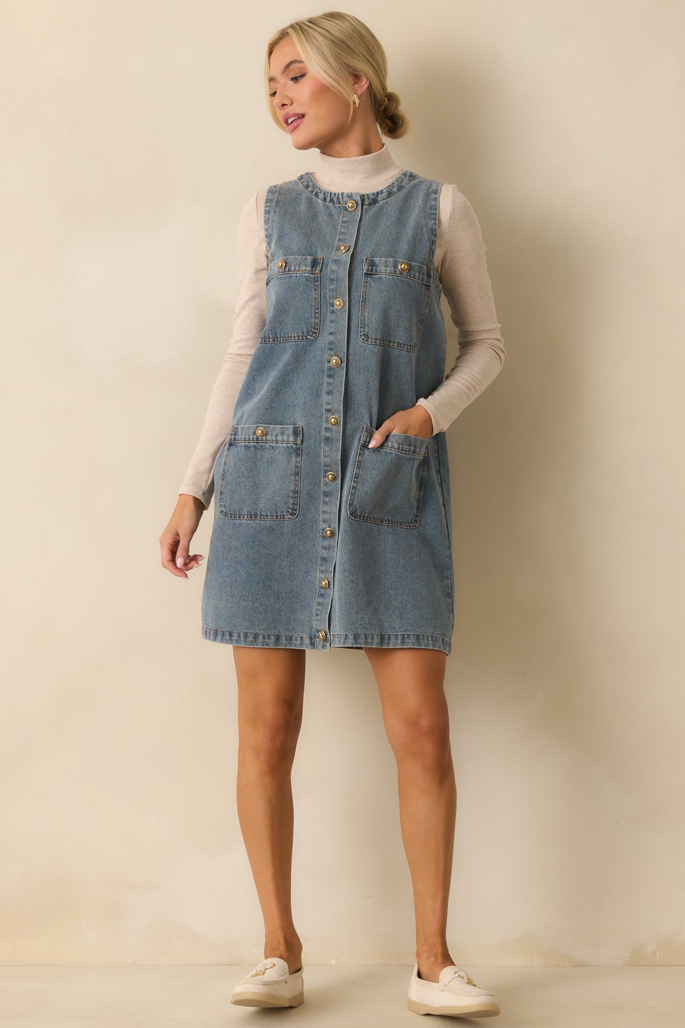 A full body front shot emphasizing the dress’s mini length and structured denim fabric.