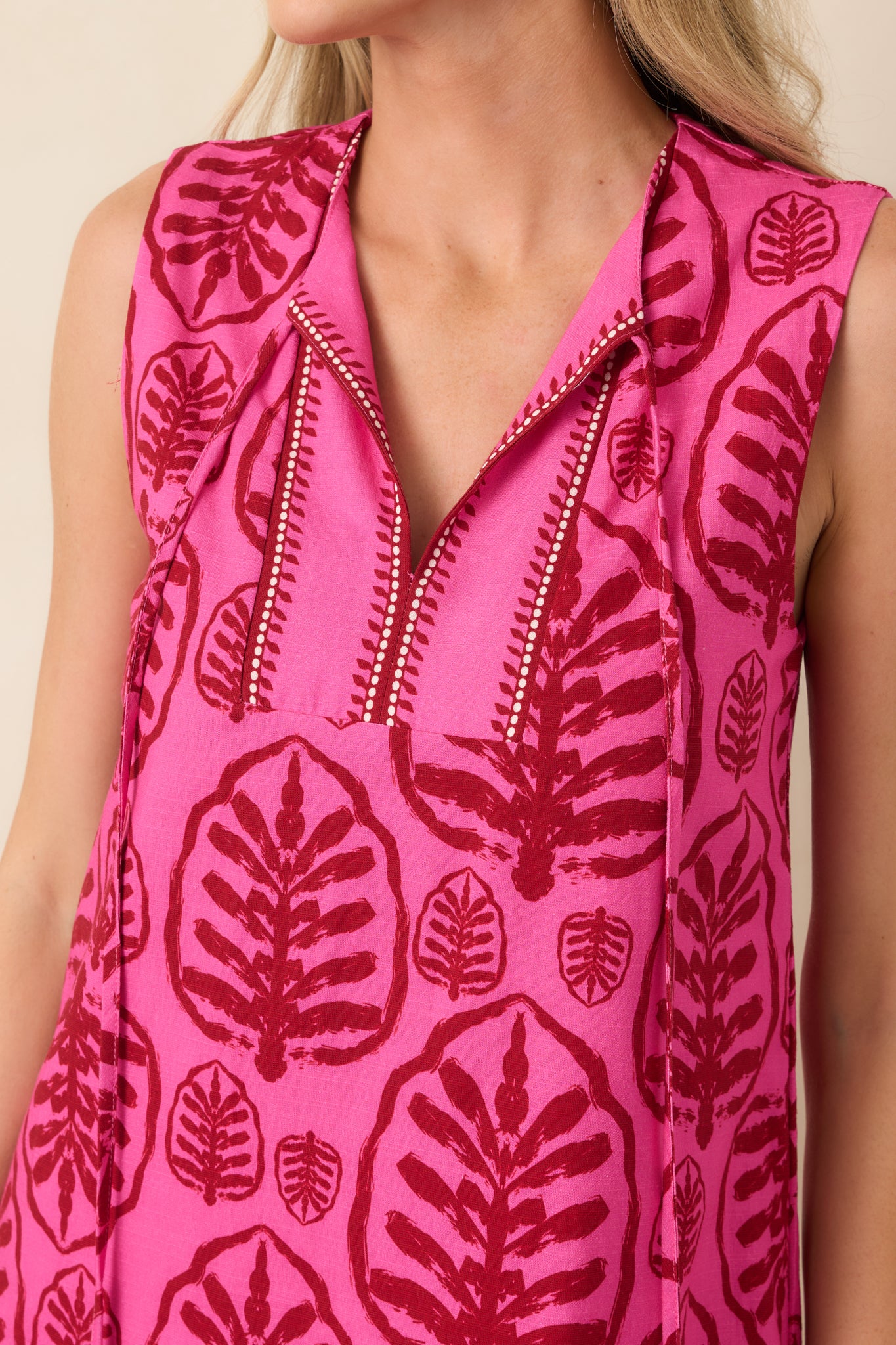 Close-up of the split neckline, contrast stitching, and long tasseled ties, highlighting the dress’s decorative details.