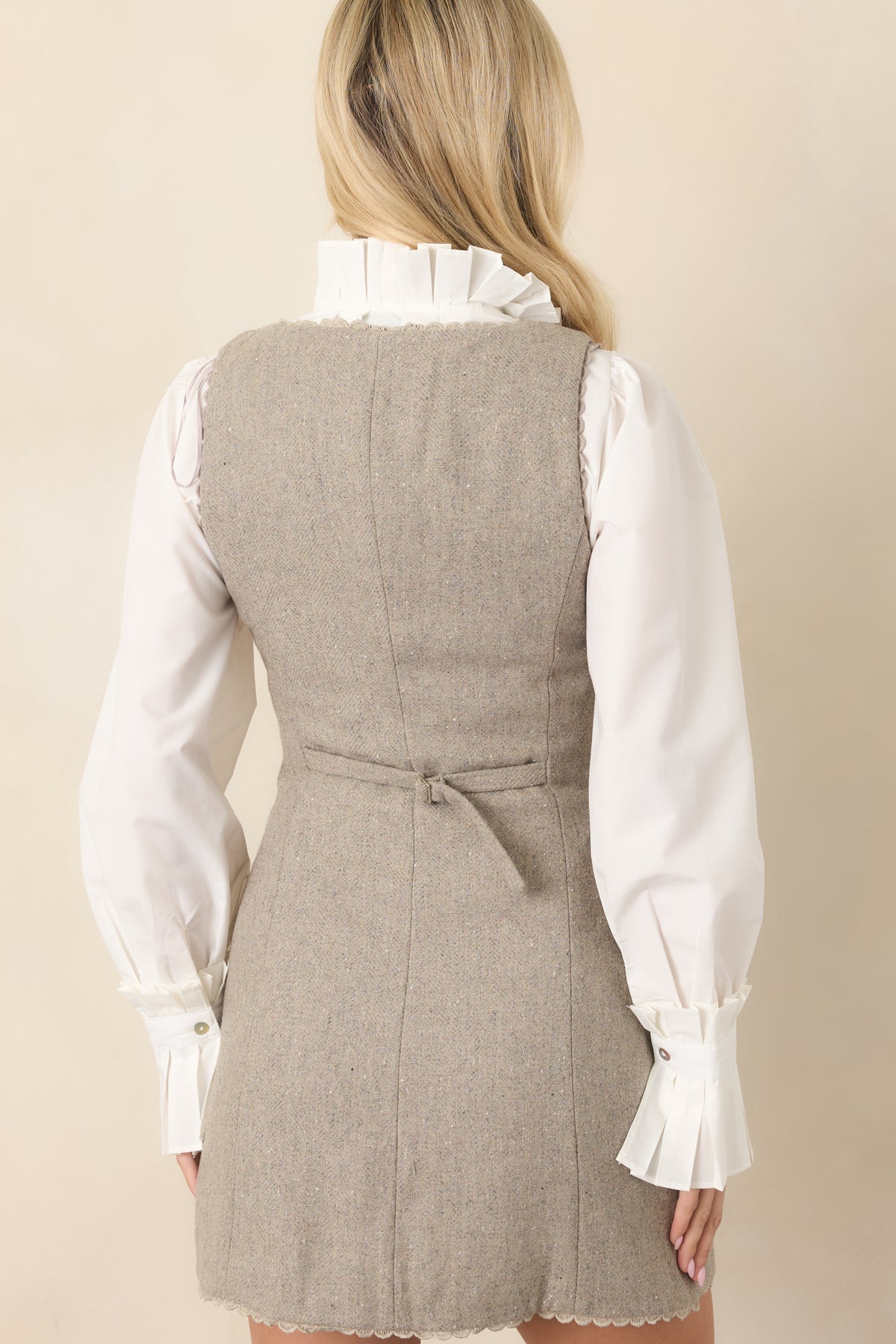 Rear view of the mini dress featuring an adjustable back belt that defines the waist and completes the fitted silhouette.