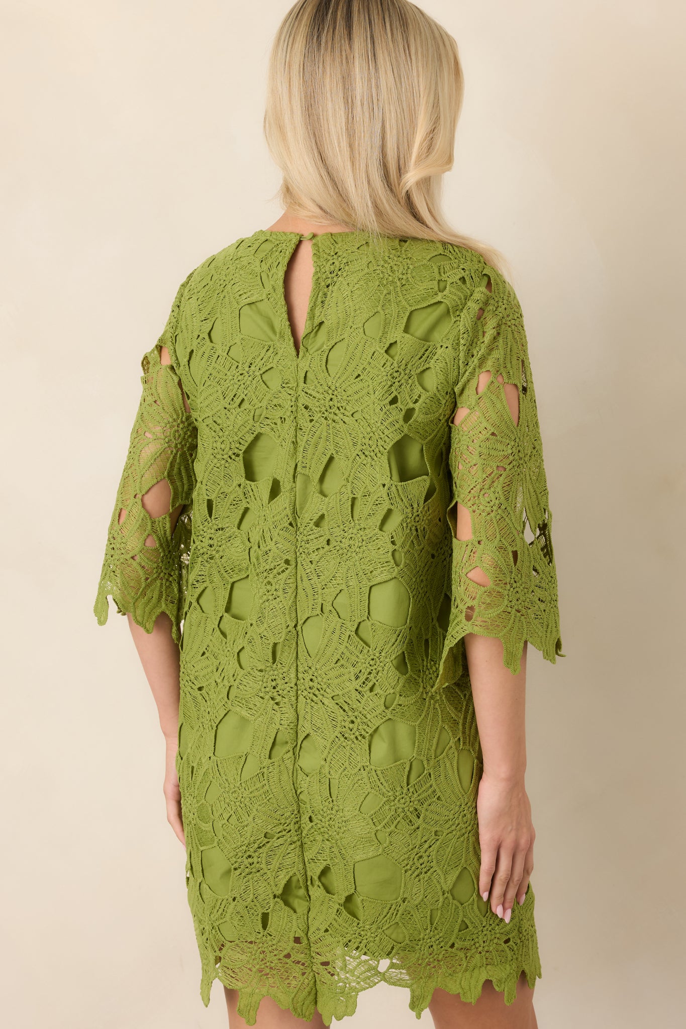 Rear view of the mini dress showing the sheer three-quarter sleeves, softly tailored shape, and back keyhole with a single button closure.