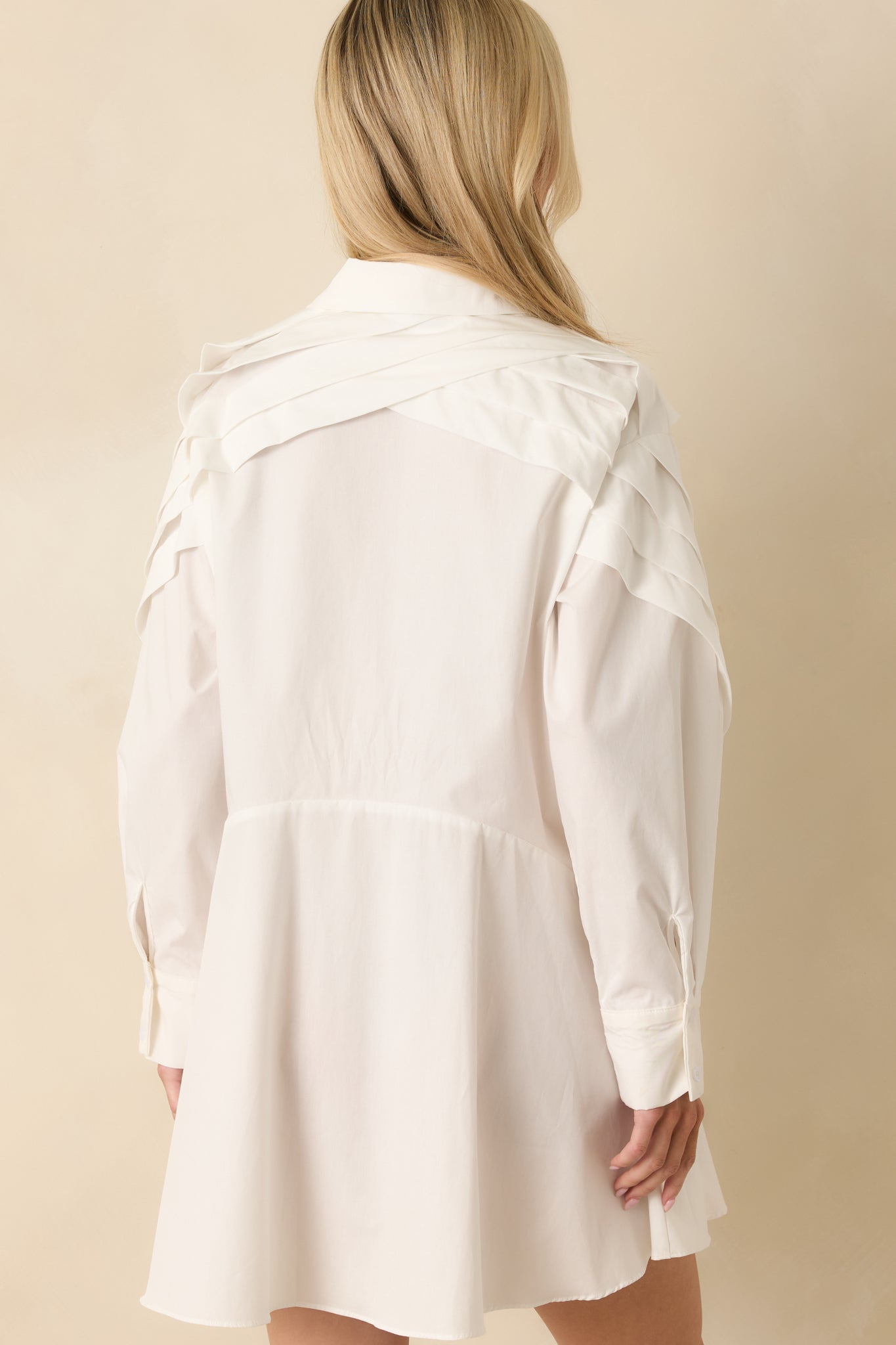 Mini dress showing relaxed fit and smooth finish with clean pleated accents.