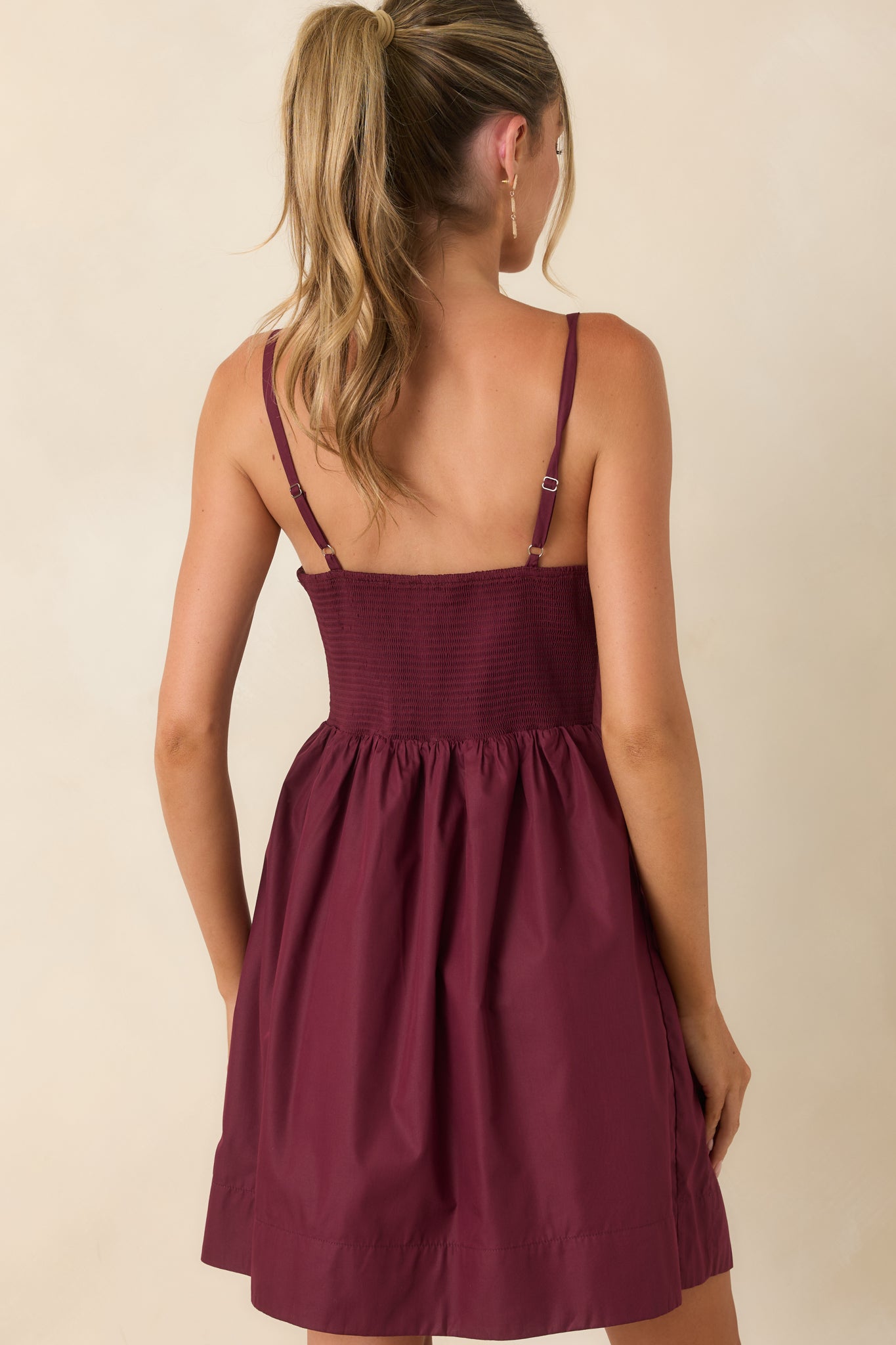 Rear view of the mini dress featuring a smocked back, adjustable straps, and gathered skirt.