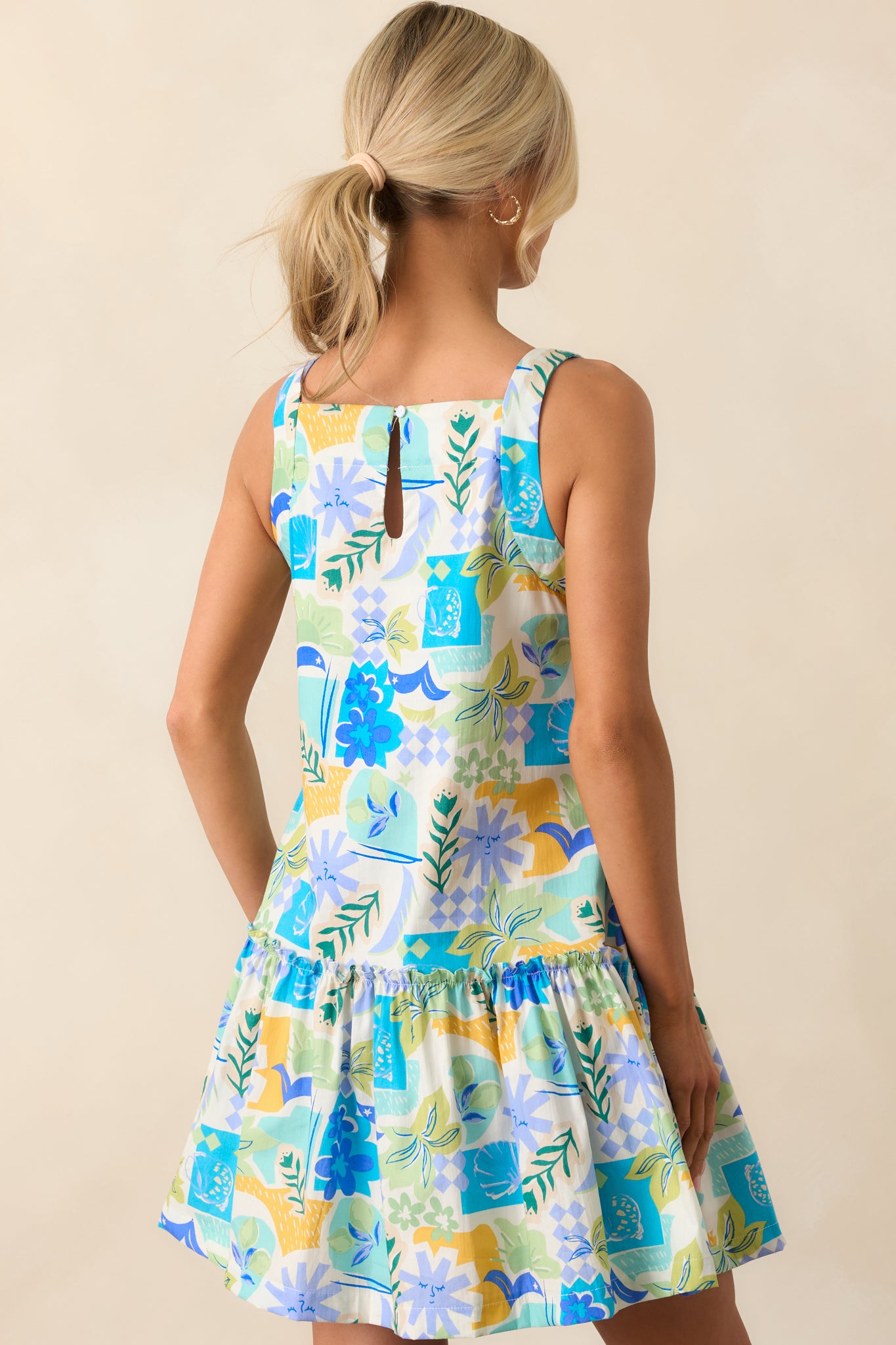 The mini dress’s rear keyhole closure and ruffle accents complement its airy silhouette and lively tropical pattern.