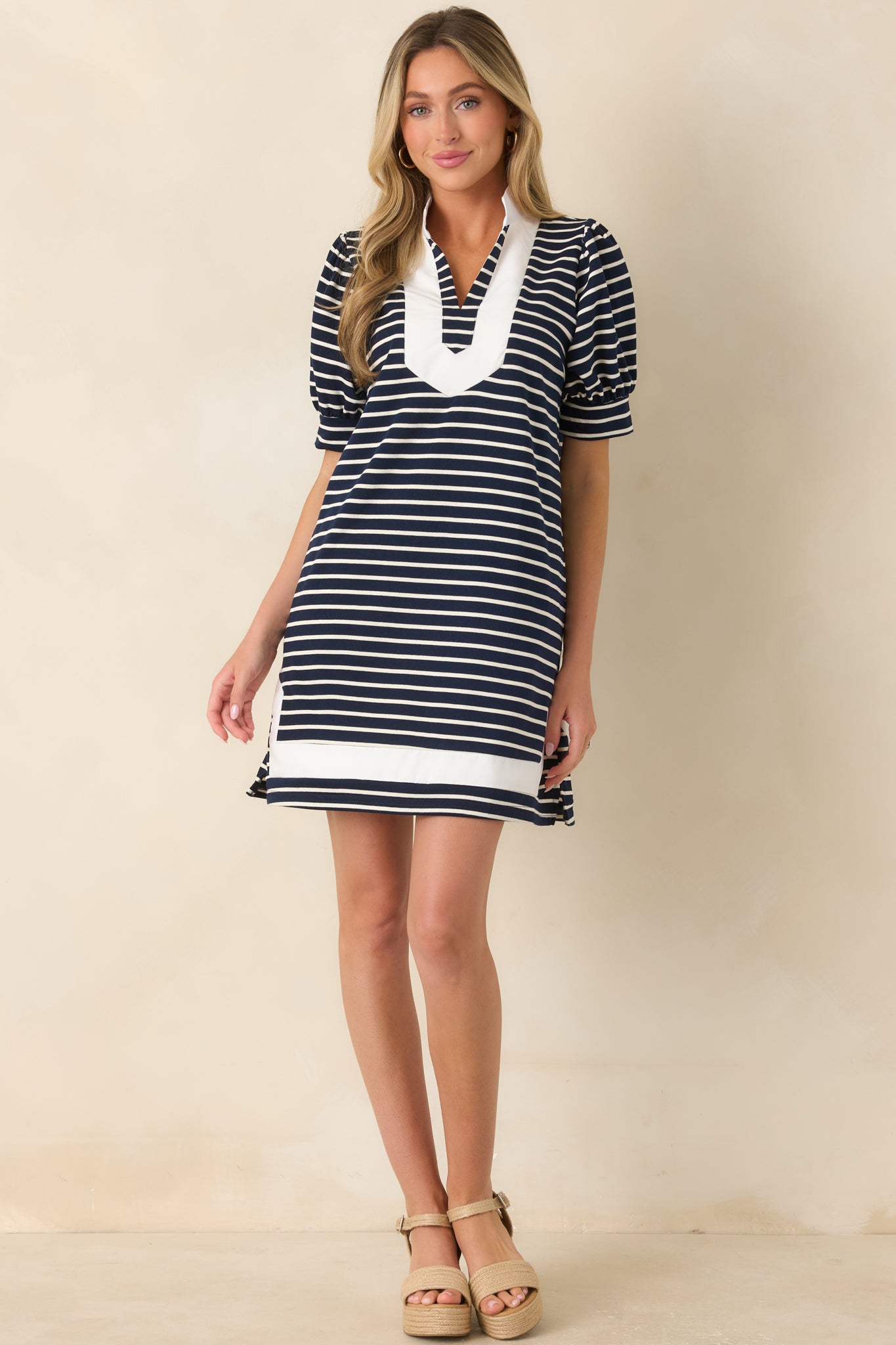 Mini shift dress in classic navy and white stripes featuring a split neckline, crisp white trim, short puff sleeves, and functional side pockets.