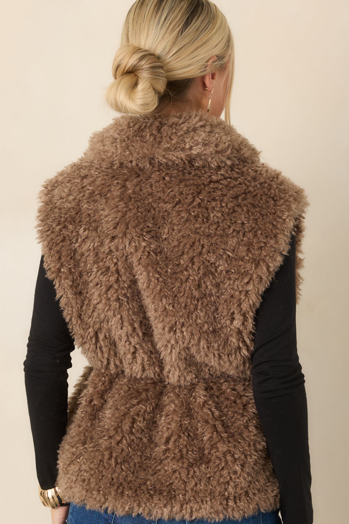 Rear of the warm mocha curly faux fur vest showing the hip-length silhouette and plush textured exterior.