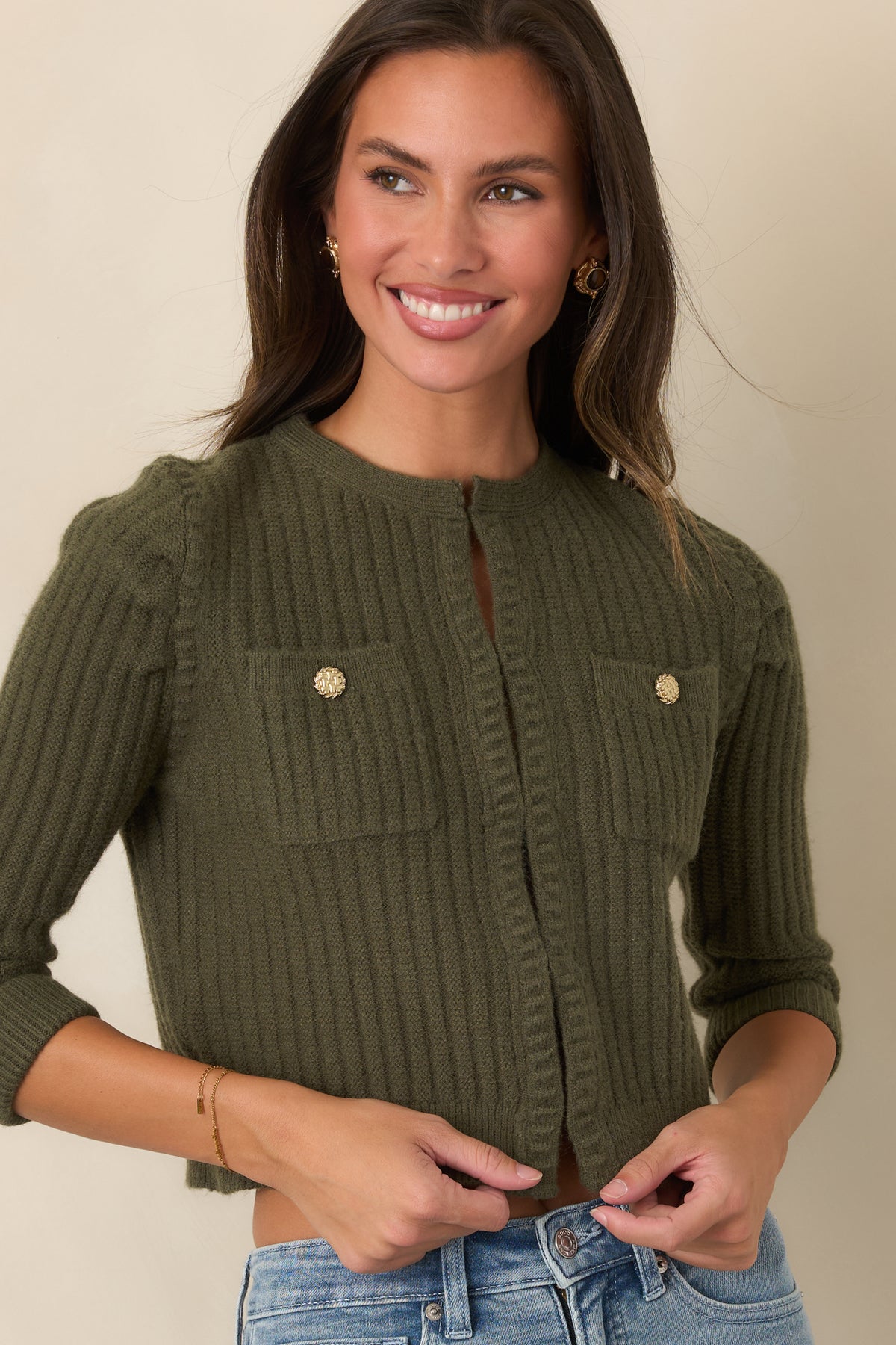 Gold-tone buttons detail the two chest pockets on this moss green ribbed cardigan.