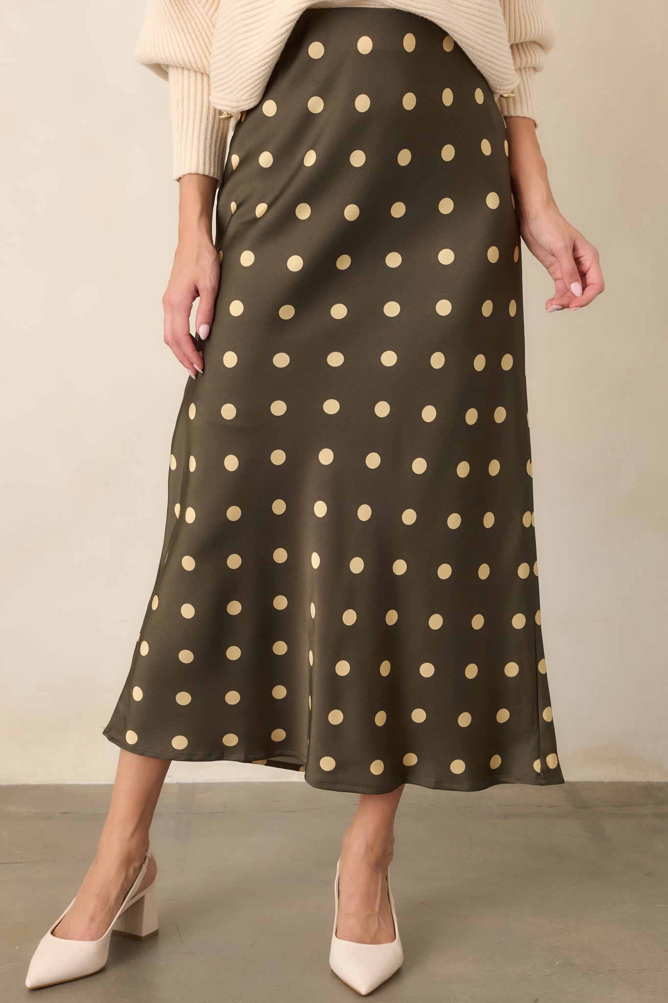 Elastic waistband and silky satin fabric create an easy, polished finish on this moss green polka dot skirt.