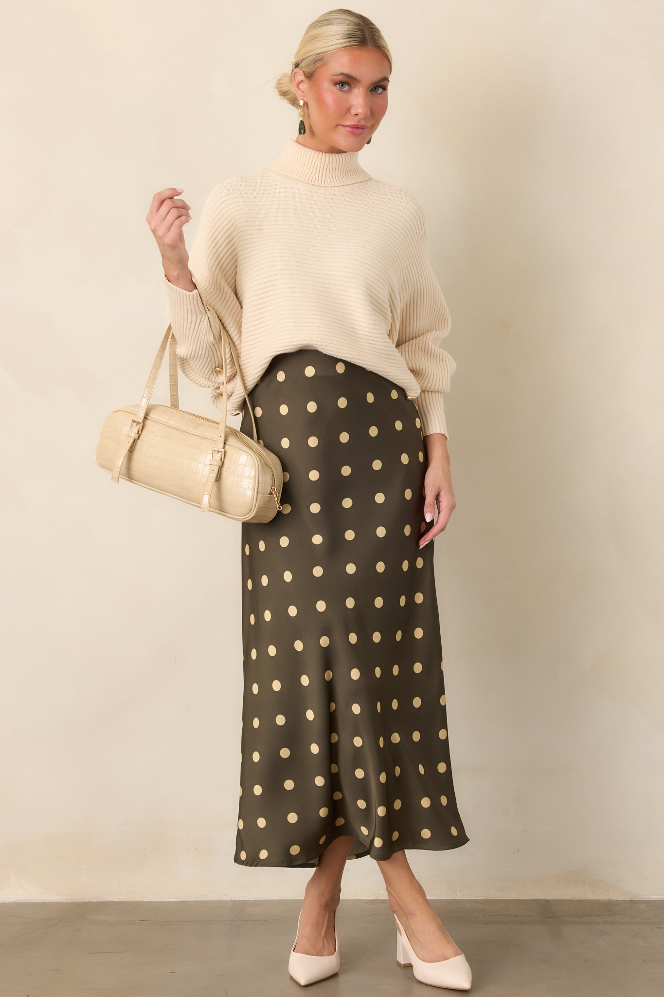 Bias-cut midi skirt with a rich moss green backdrop, classic cream dots, and an elegant draped silhouette.