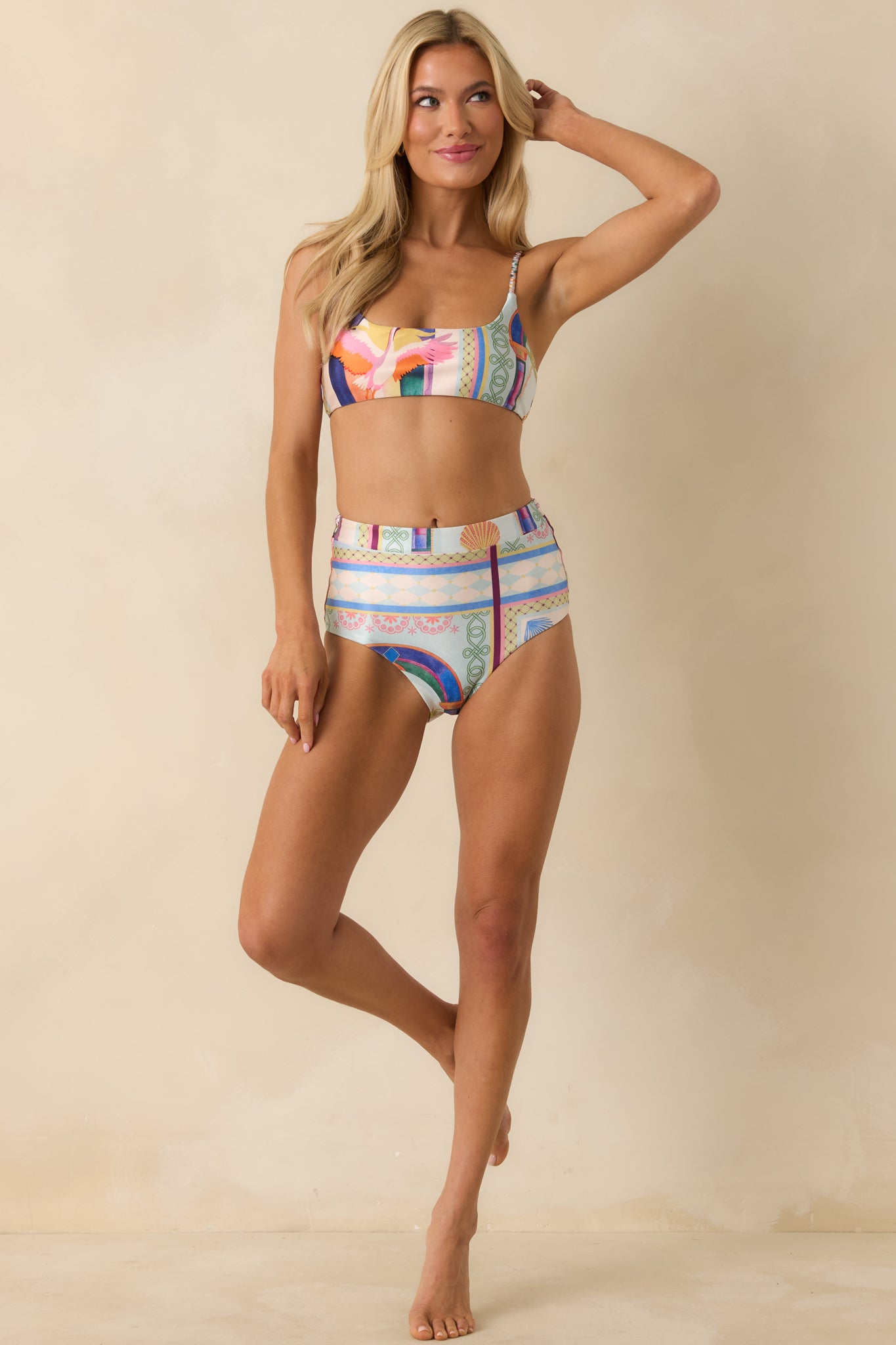 Multi-colored bikini top with tropical print, scoop neckline, and adjustable braided straps.
