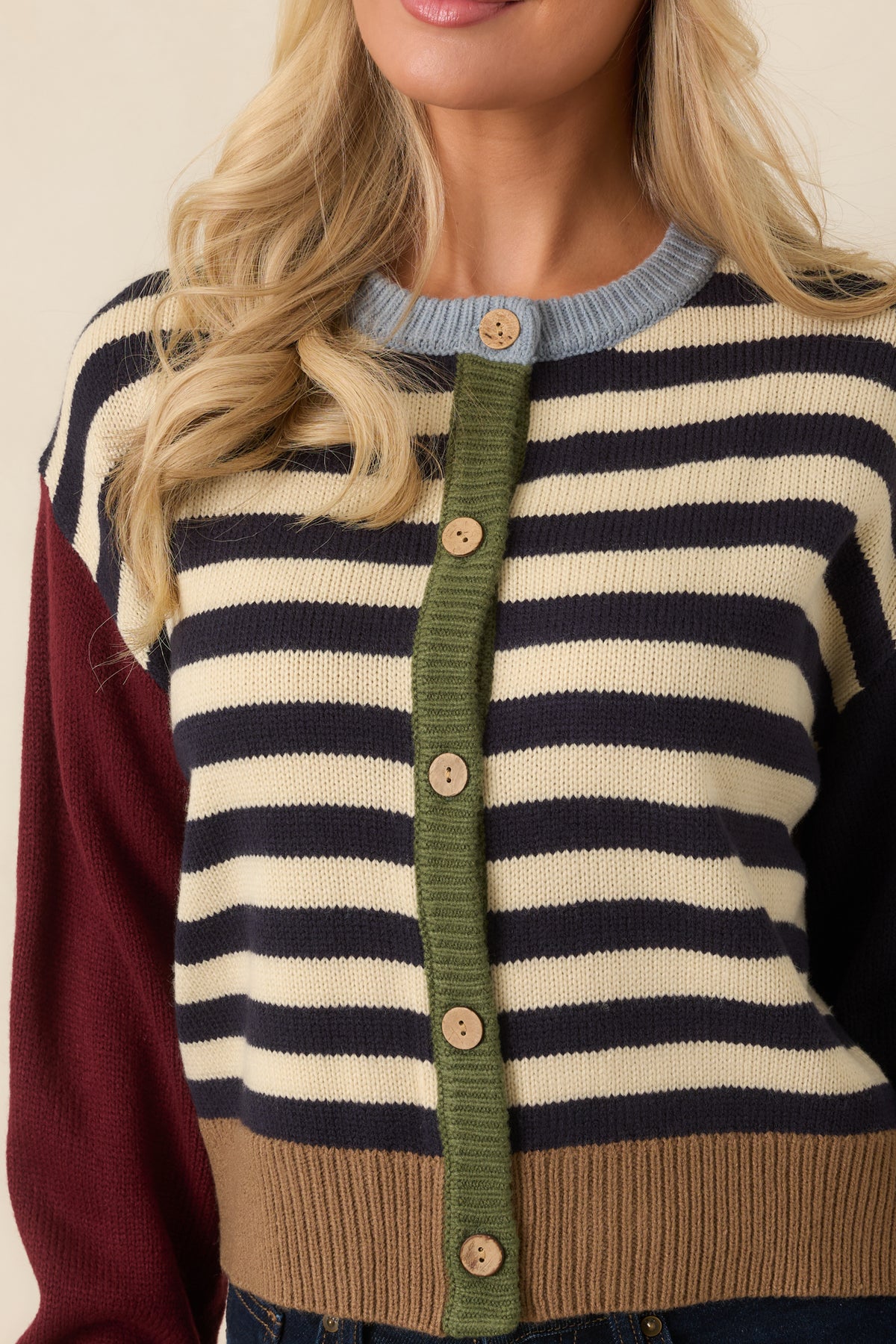 Contrasting knit textures highlight the light blue neckline, burgundy sleeve fabric, and navy ribbed cuff.
