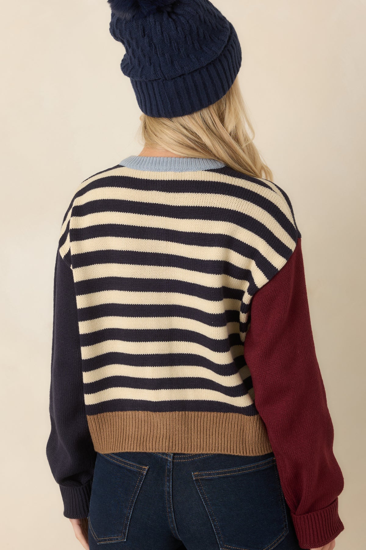 Rear of the multicolor knit cardigan showing horizontal stripes, long contrast sleeves, and a camel ribbed hem.