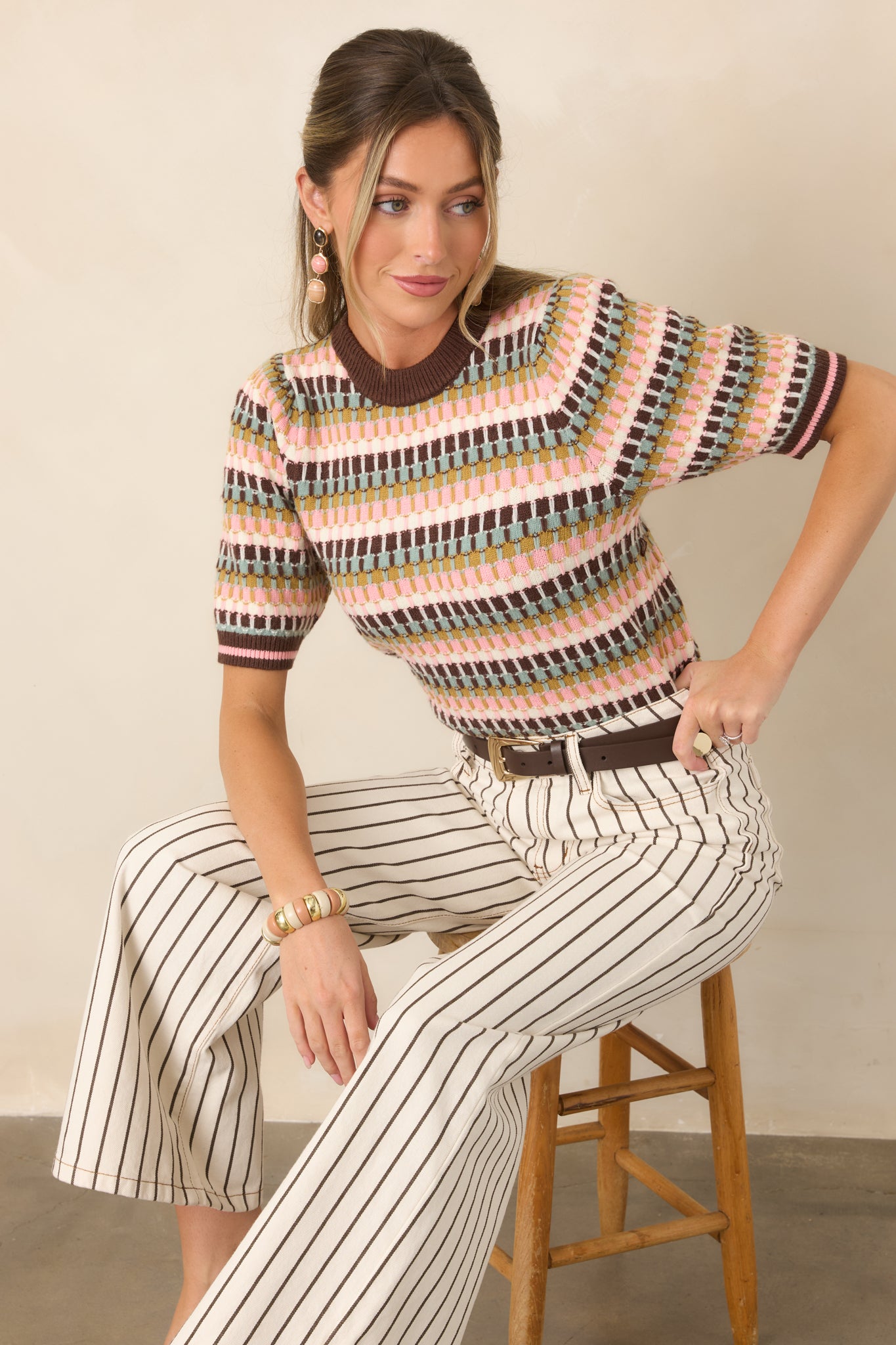 Multicolor striped knit top featuring textured brown, sage, olive, blush pink, and ivory stripes with chocolate brown ribbed trim and pink accents.