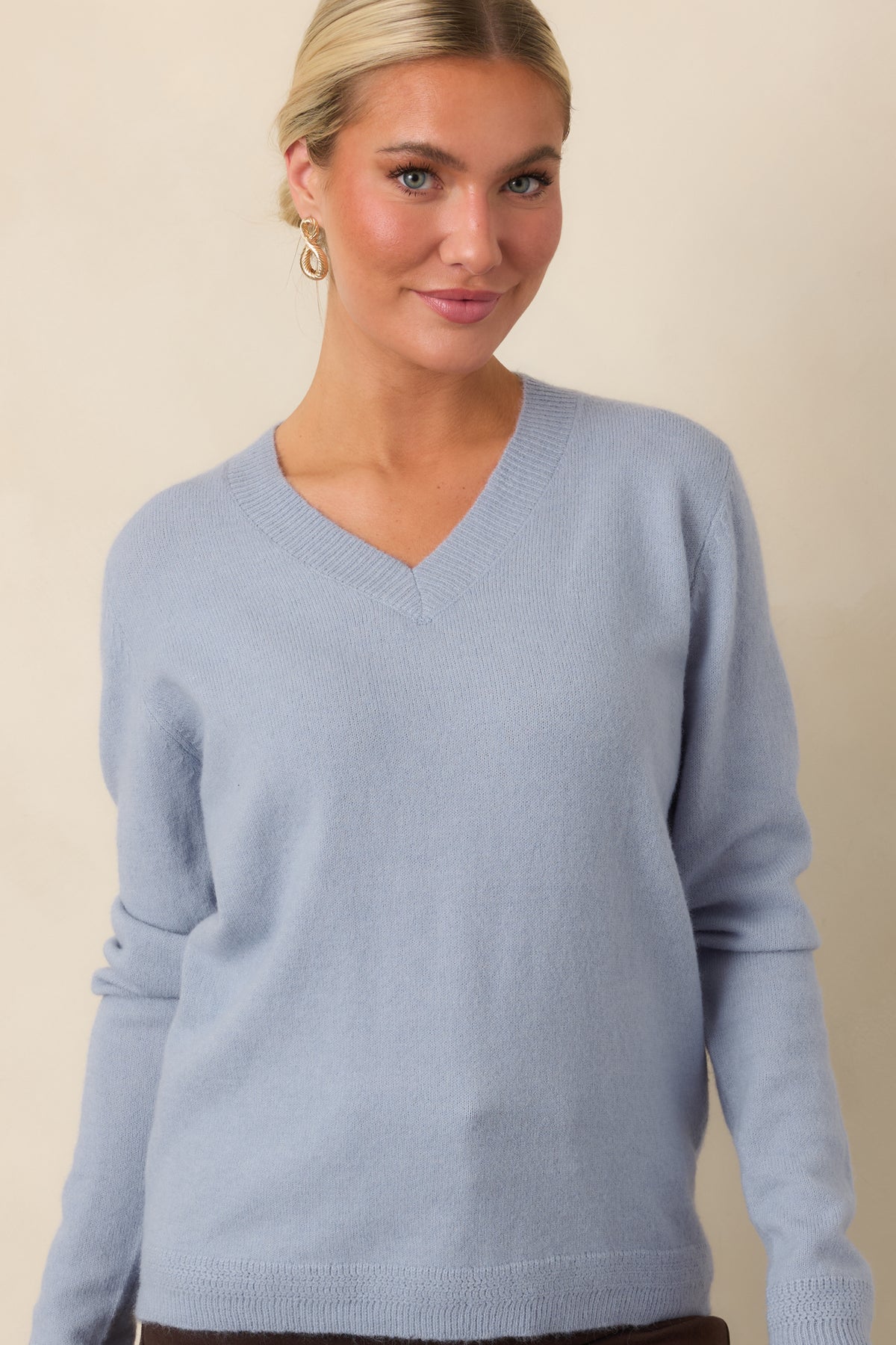 Muted blue knit top emphasizing its relaxed shape and softly finished ribbed edges.