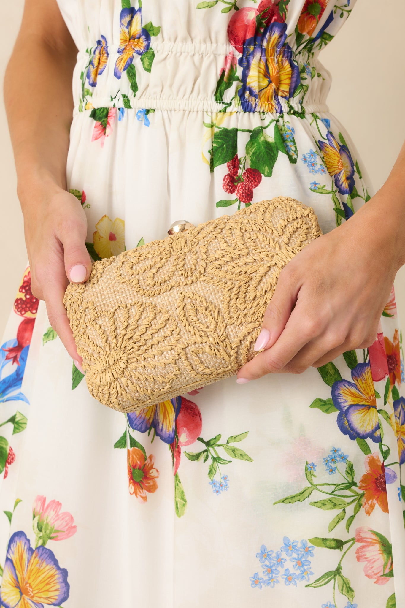 Natural raffia clutch featuring a structured silhouette, woven floral texture, and secure clasp closure.